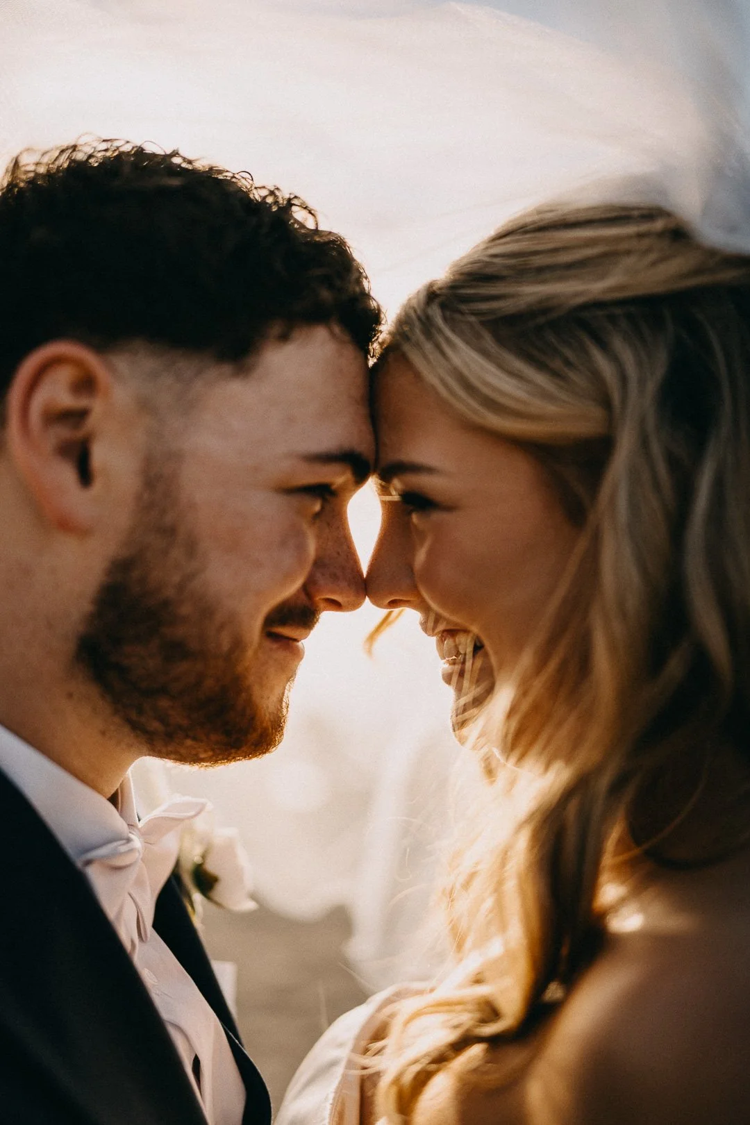 Bride and groom embracing under the veil during sunset wedding portraits