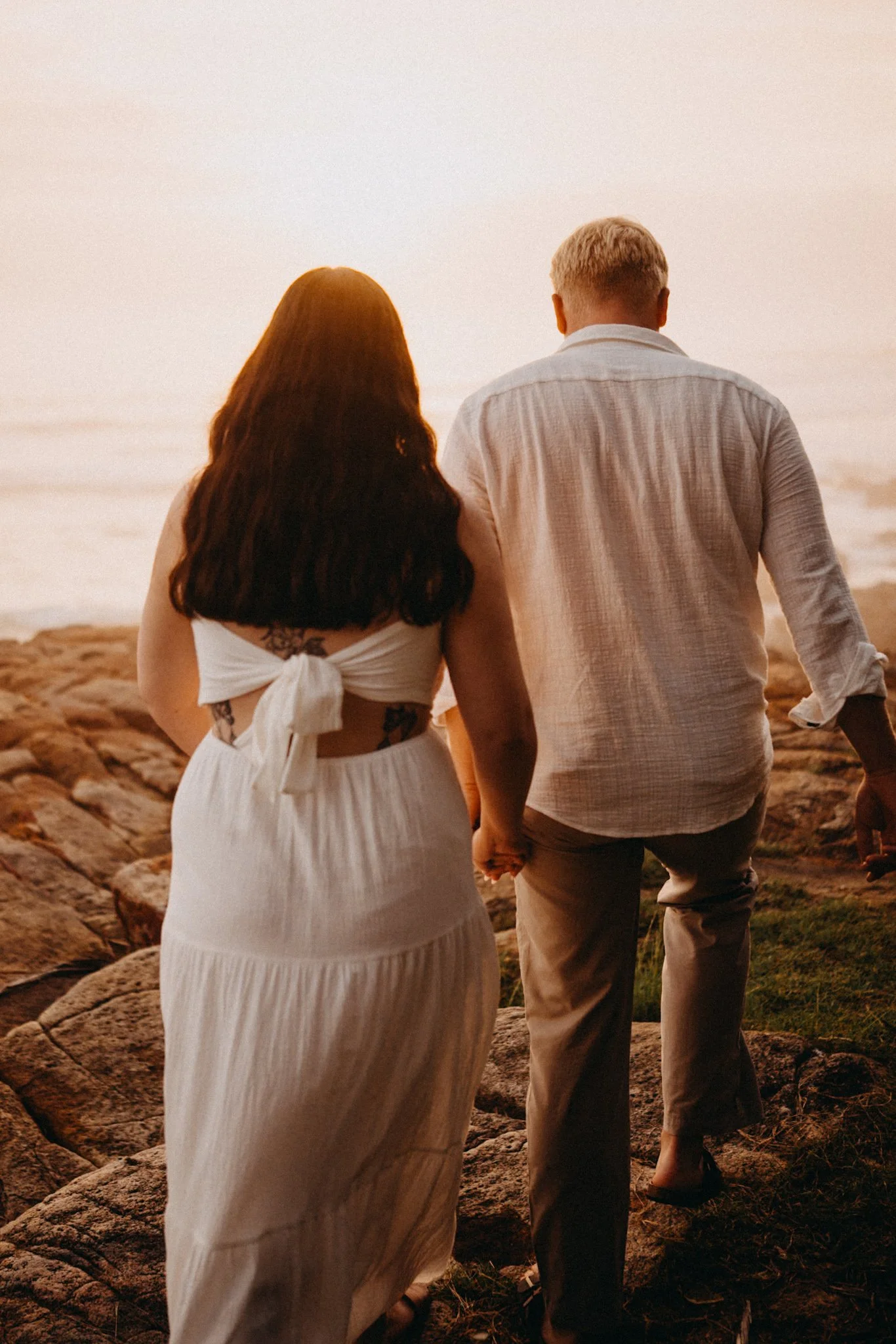 Bride and groom walk along rocks to begin ceremony at Coolum Beach at sunrise