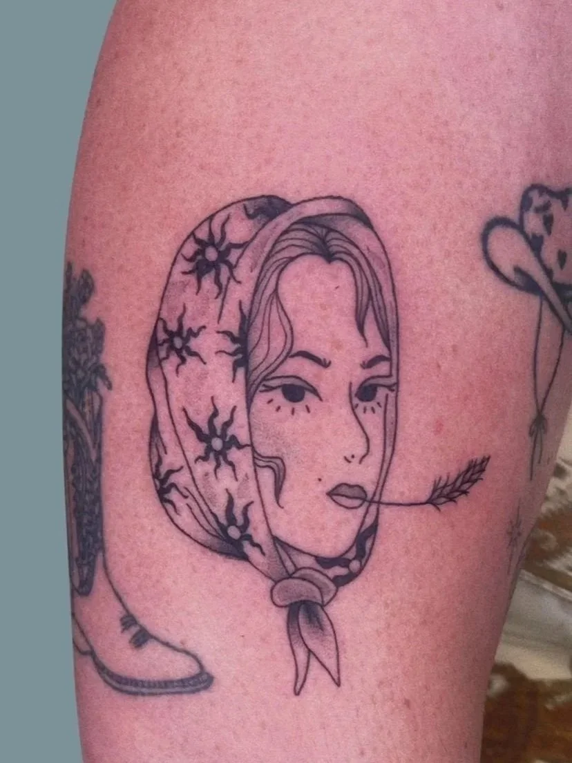 Black ink line drawing of a woman's face with detailed eyes, lips, and hair, wearing a headscarf with a star pattern, and a feather in her mouth.