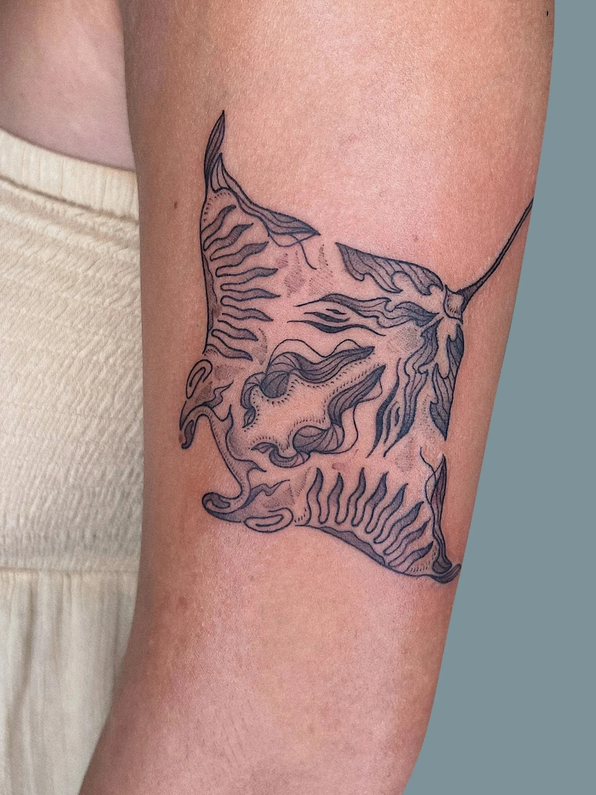 Line art tattoo of a lion's face on a person's upper arm.