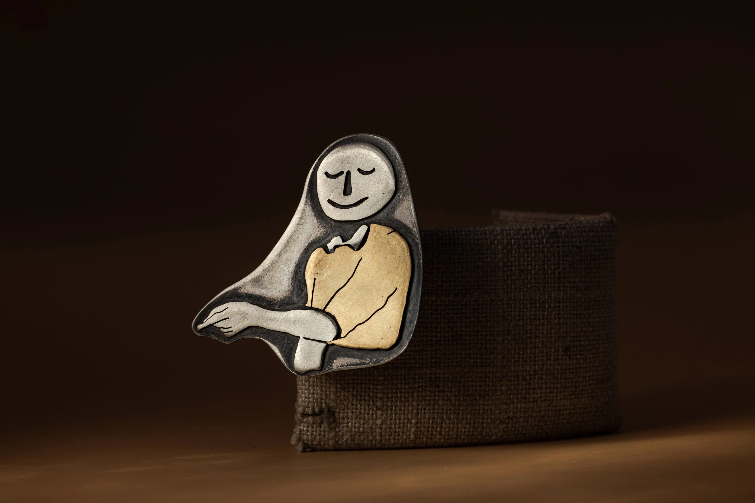 "Men I Trust" pin. Sterling silver and brass. Photo by Jeff Dietrich