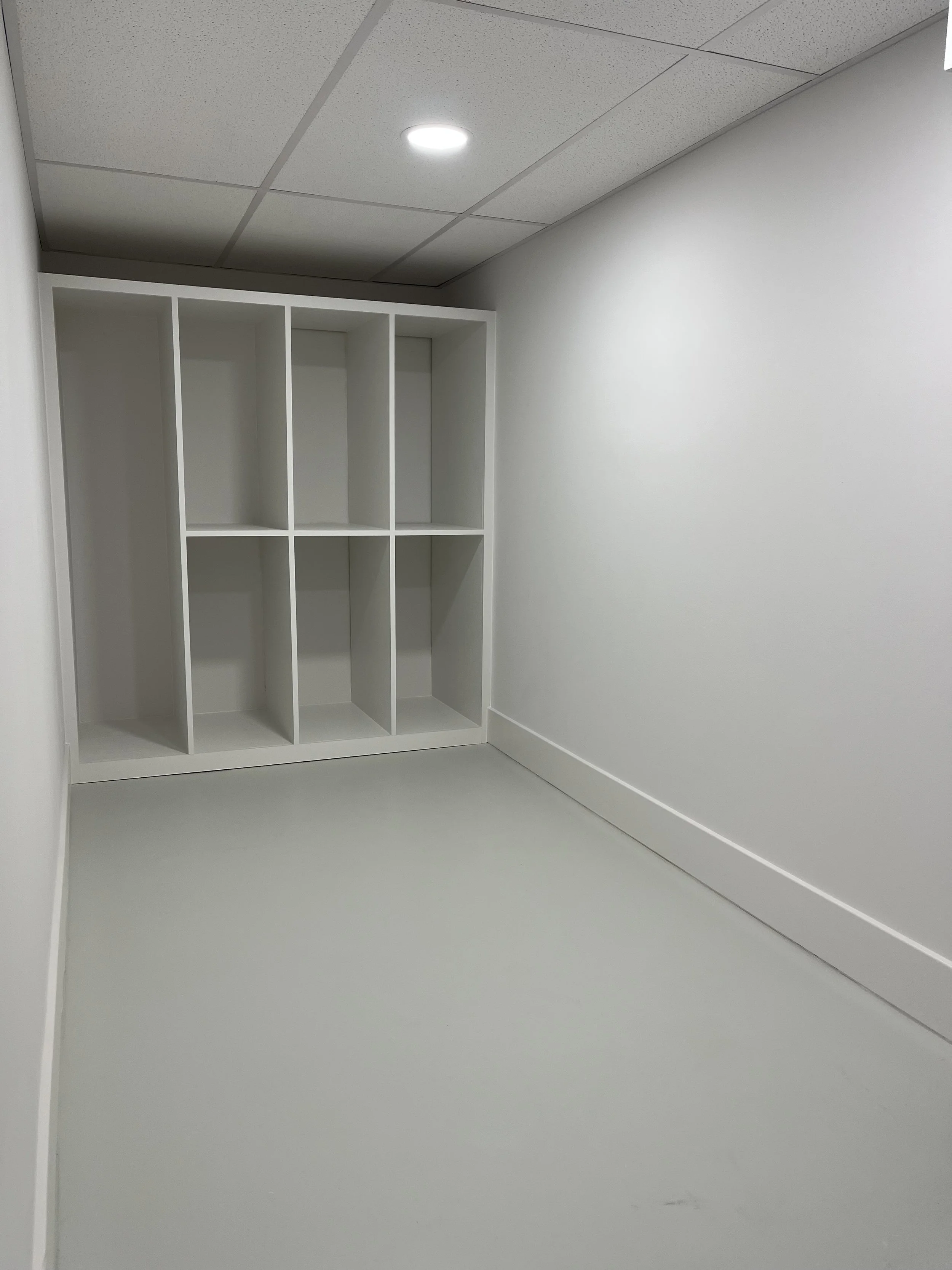 Empty white room with a white storage unit and a ceiling light.
