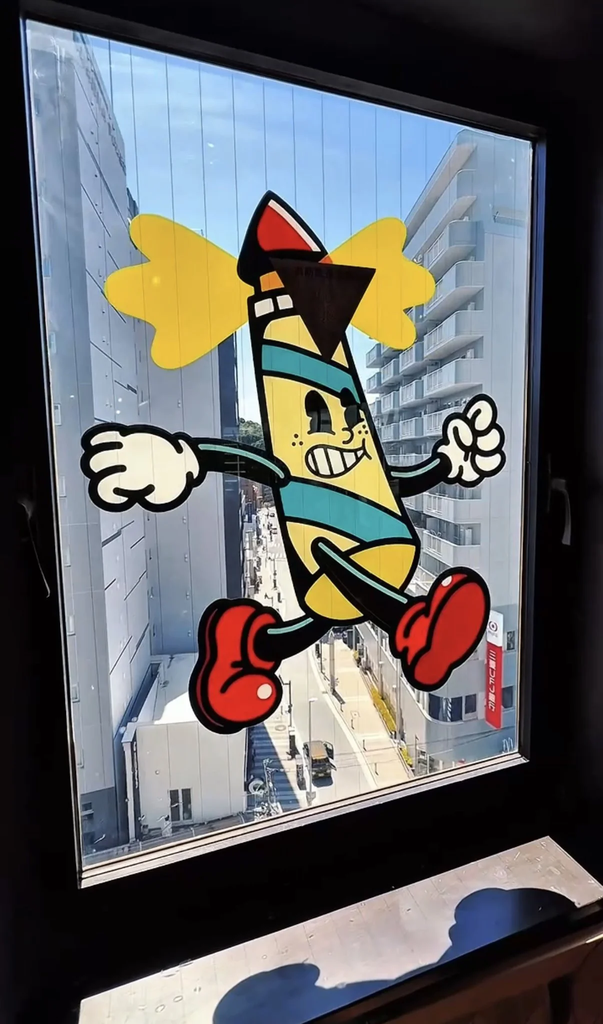 Colorful cartoon depiction of a character with a yellow body, red shoes, and a red, black, and teal hat, running with a cheerful expression on a window with city buildings in the background.