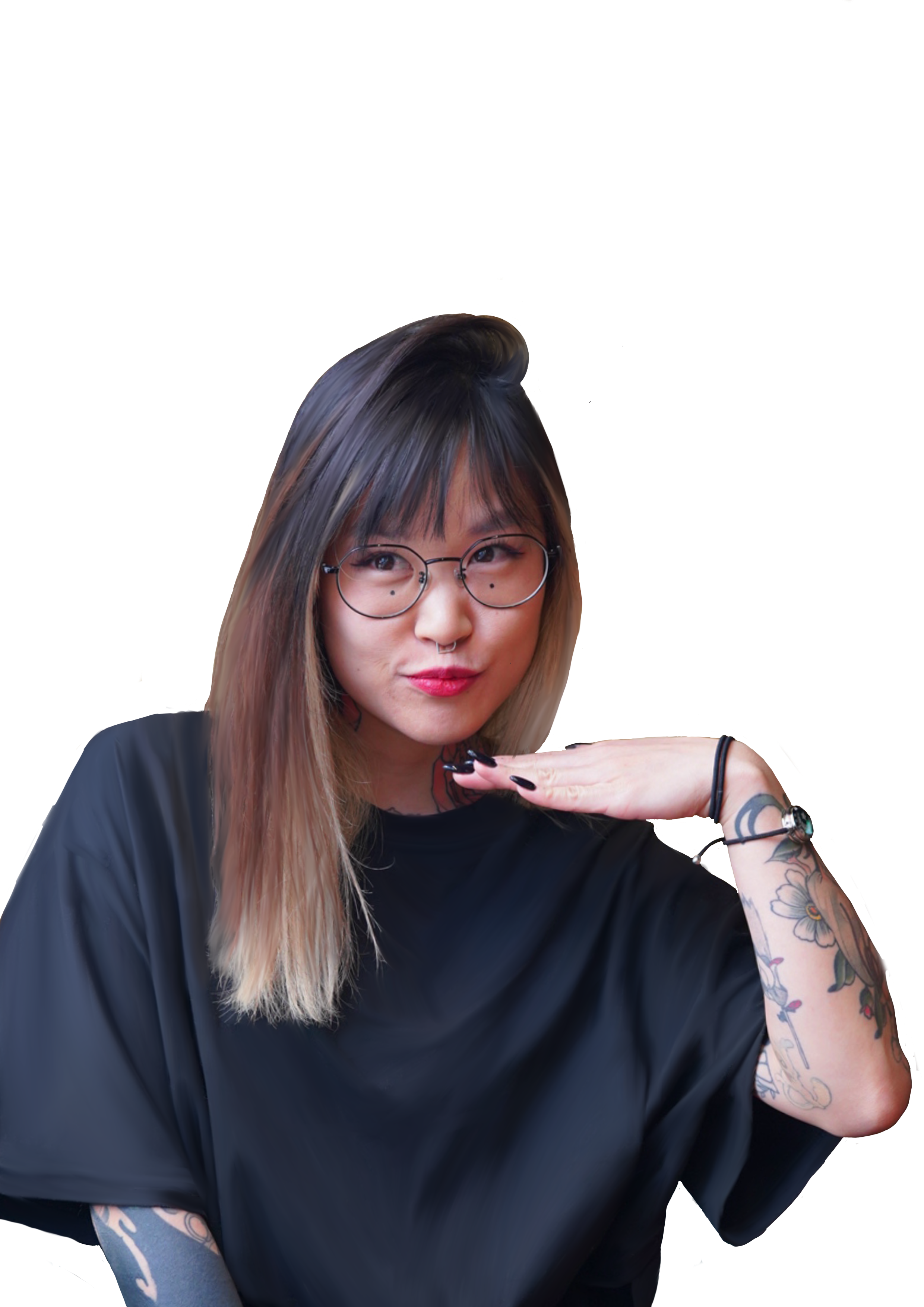 A young woman with long hair, glasses, and tattoos on her arm, wearing a black shirt, making a playful pose with her fingers touching her chin and looking to the side.