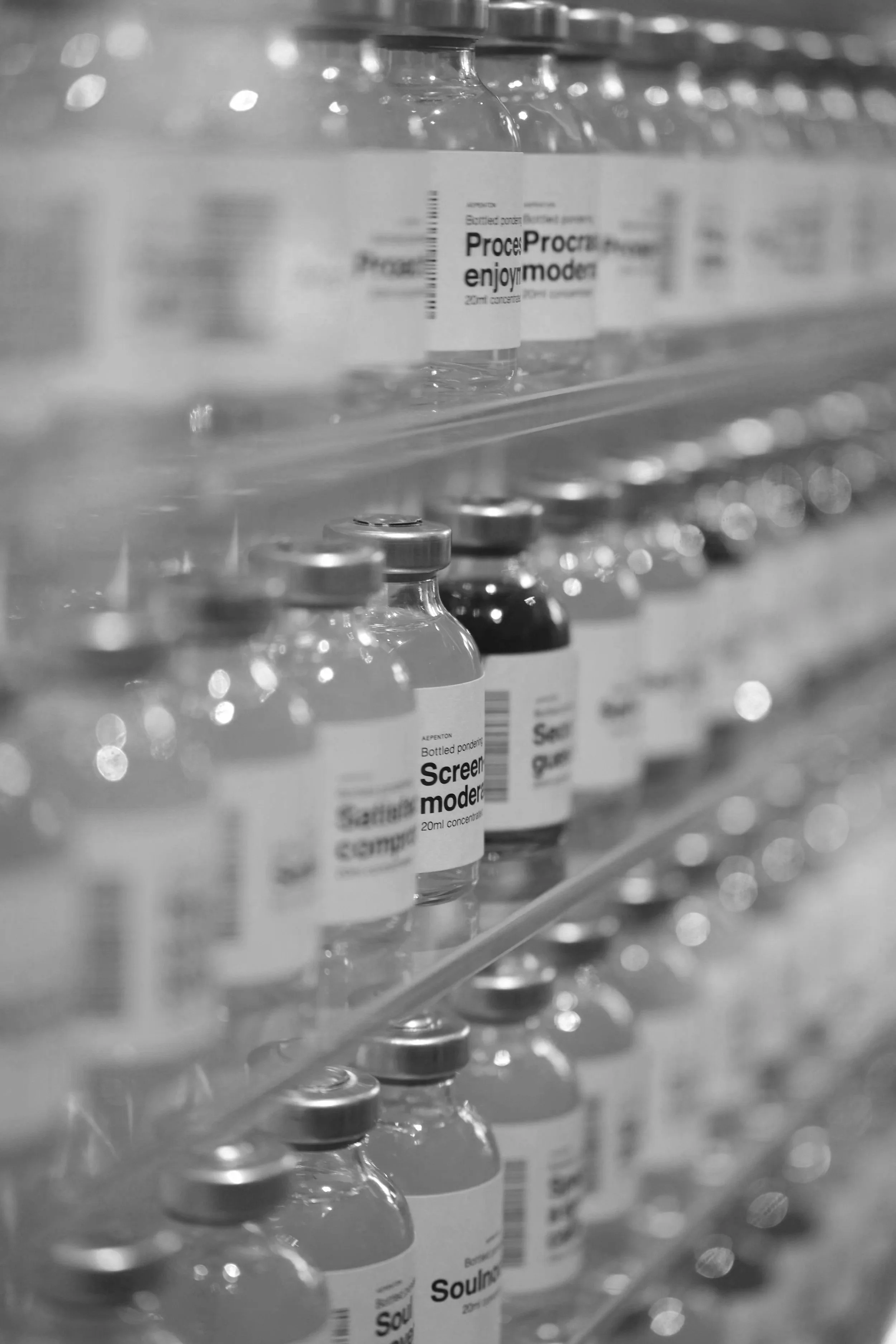 Shelf of glass bottles filled with liquids, with labels reading 'Processing enjoyment,' 'Screen modern,' and 'Soul.'
