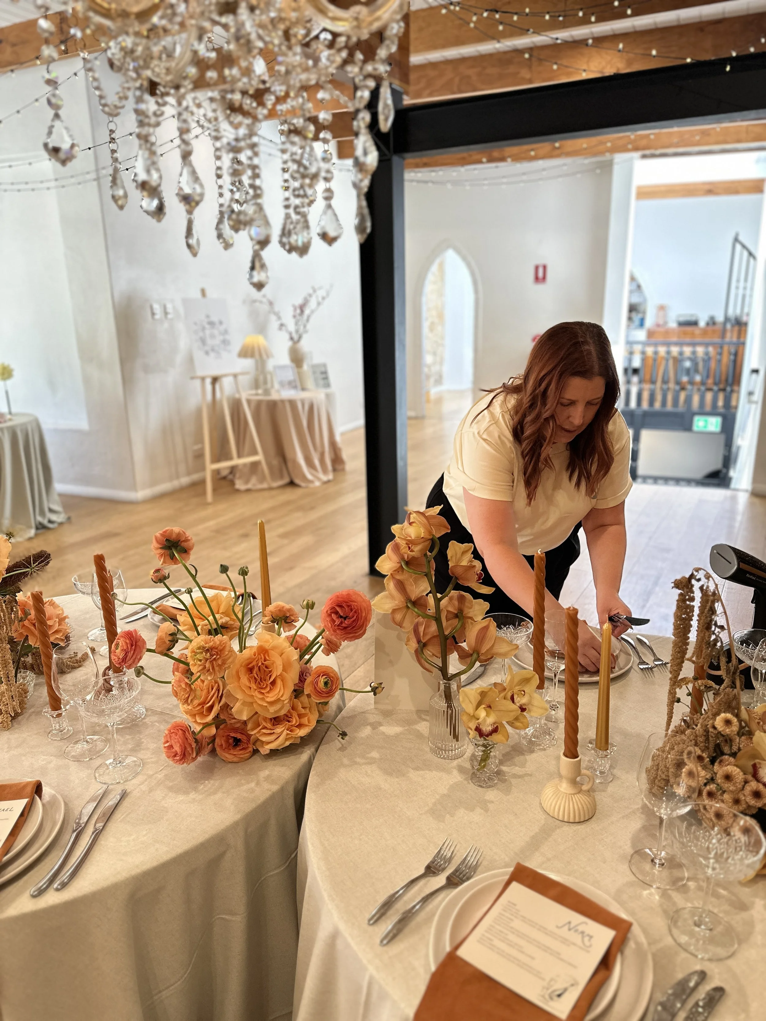 A table scape being setup by Emma from Sparrow Weddings & Events, at the Manor Basket Range. Menus, Table Number & Stationery by Nutmeg Creative. Florals by Sweet Nothings Flowers. Hire items by Honoured Hire.