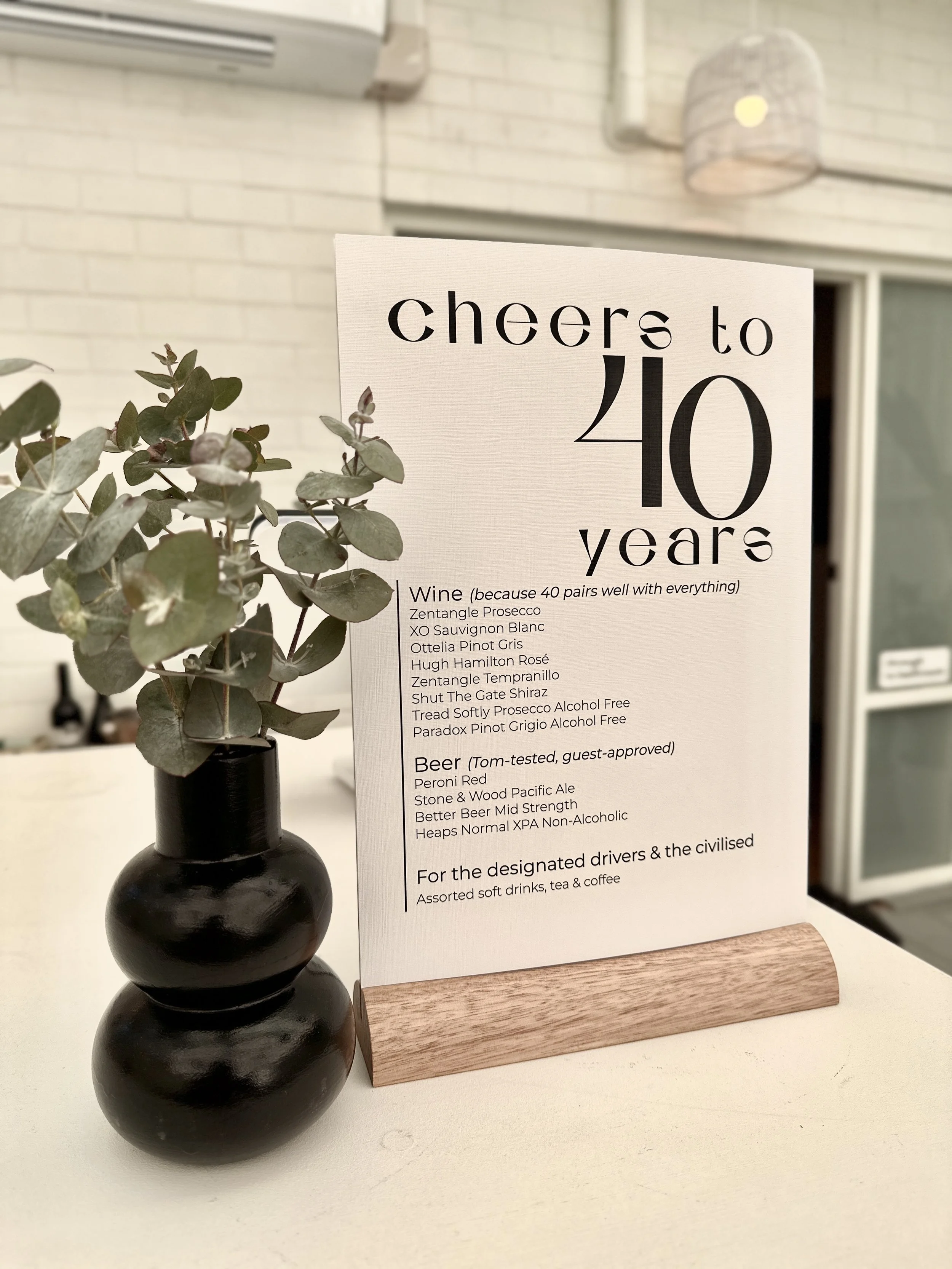 A drinks menu on the bar at Sublime Social, Clarence Park. Sign reads ' cheers to 40 years' and lists drinks available, designs by Nutmeg Creative. Sublime Café & Catering, Adelaide South Australia