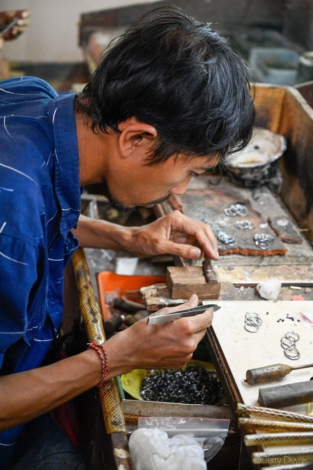 A man working at a jewelry workshop, crafting rings and jewelry.