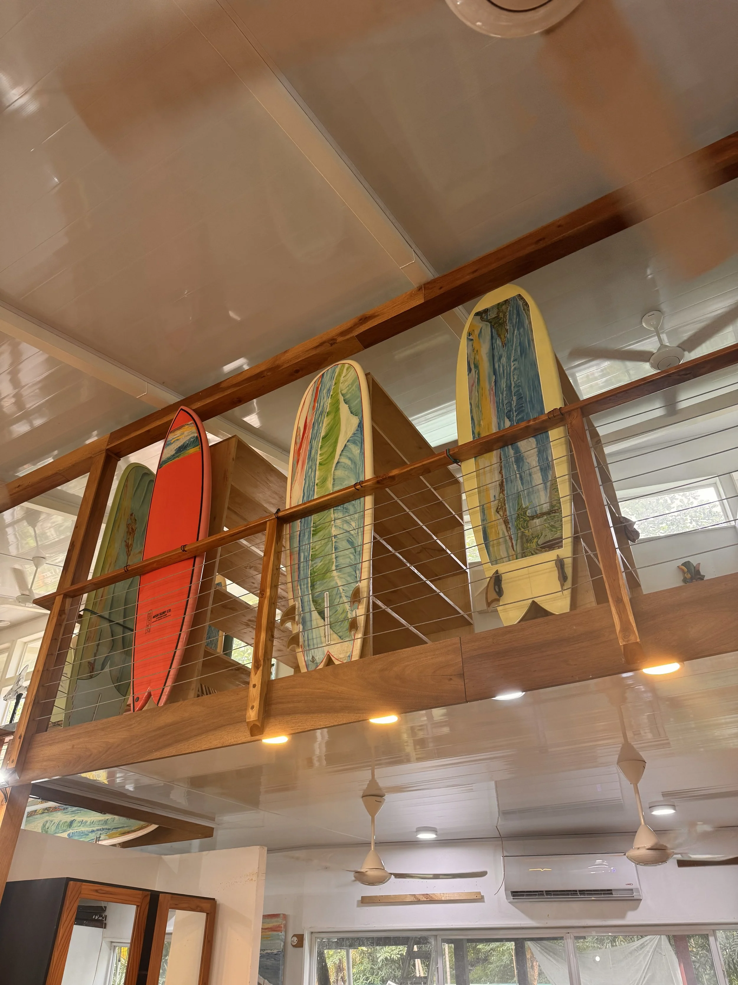 Multiple colorful surfboards displayed on a wooden balcony inside a house.