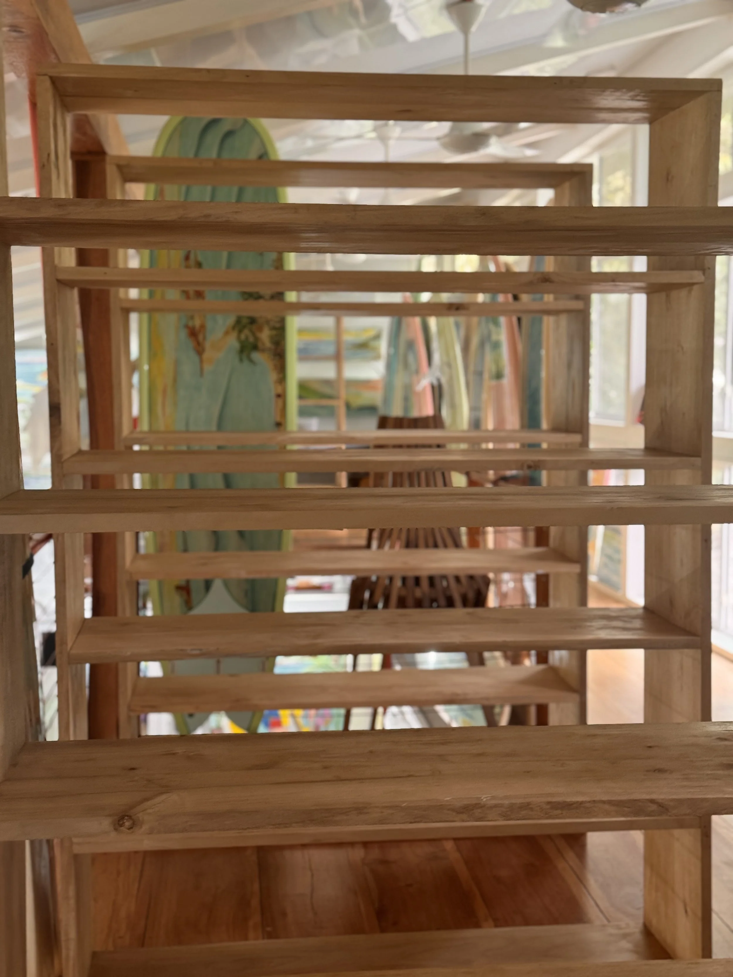 View through wooden staircase overlooking surfboards and outdoor space