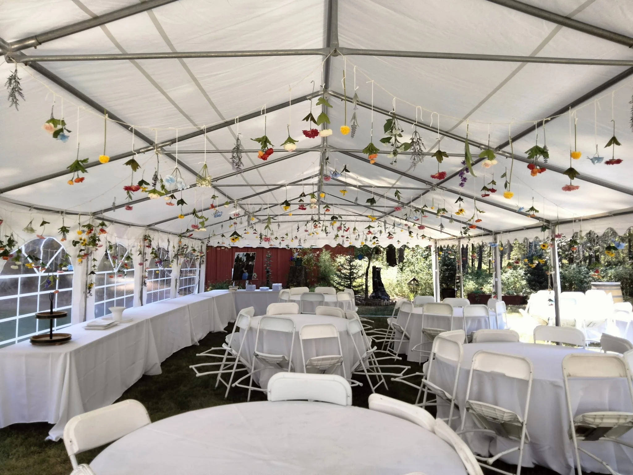 Tent decorated with hanging flowers, set up for an outdoor event with tables and chairs.