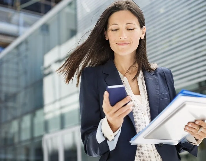 Business woman happily looking at a notification on her phone.
