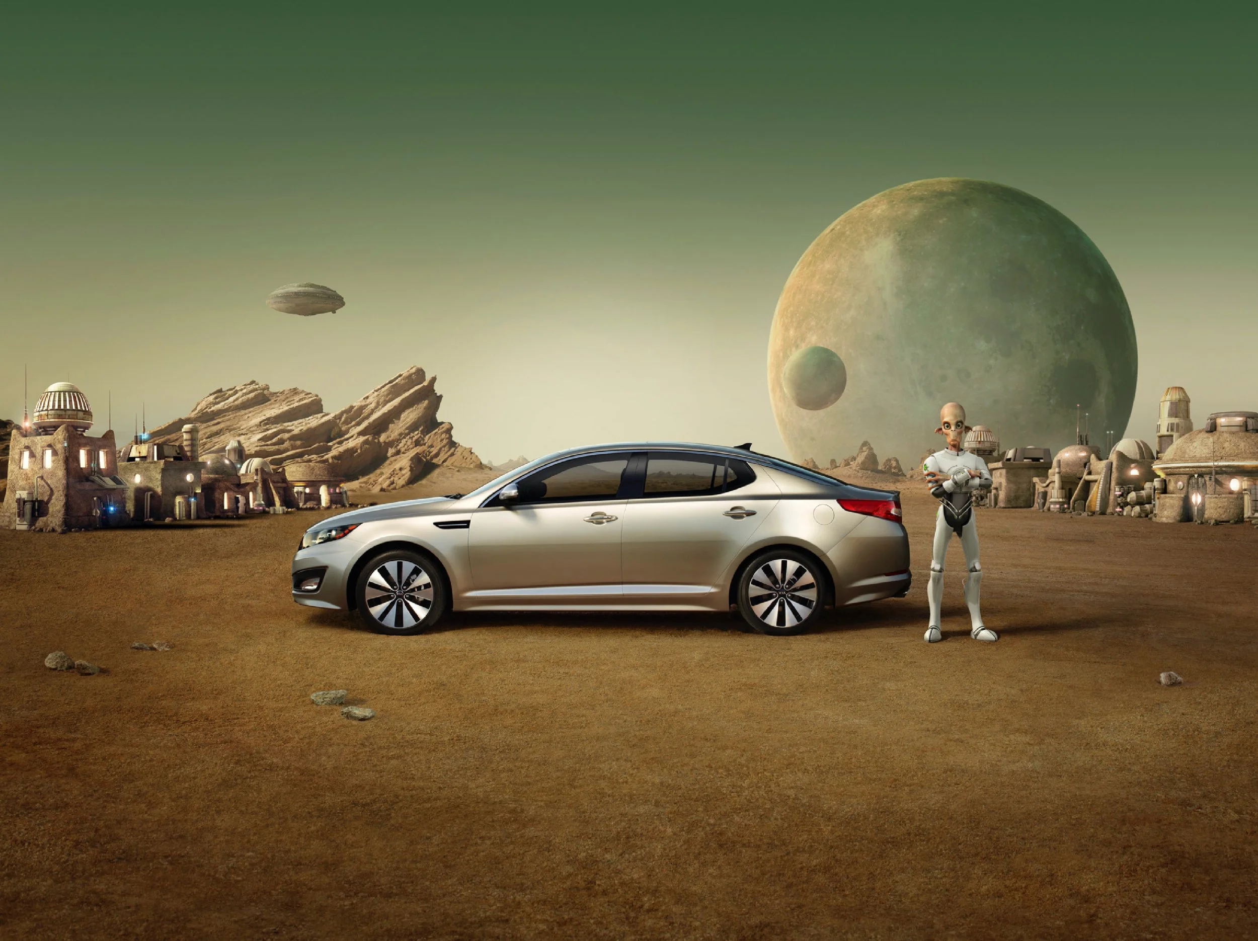 A silver car parked on a desert landscape with a friendly robot standing nearby, in front of a futuristic settlement with domed buildings and rocky formations, with a large planet and moons in the sky, suggesting an alien or science fiction setting.