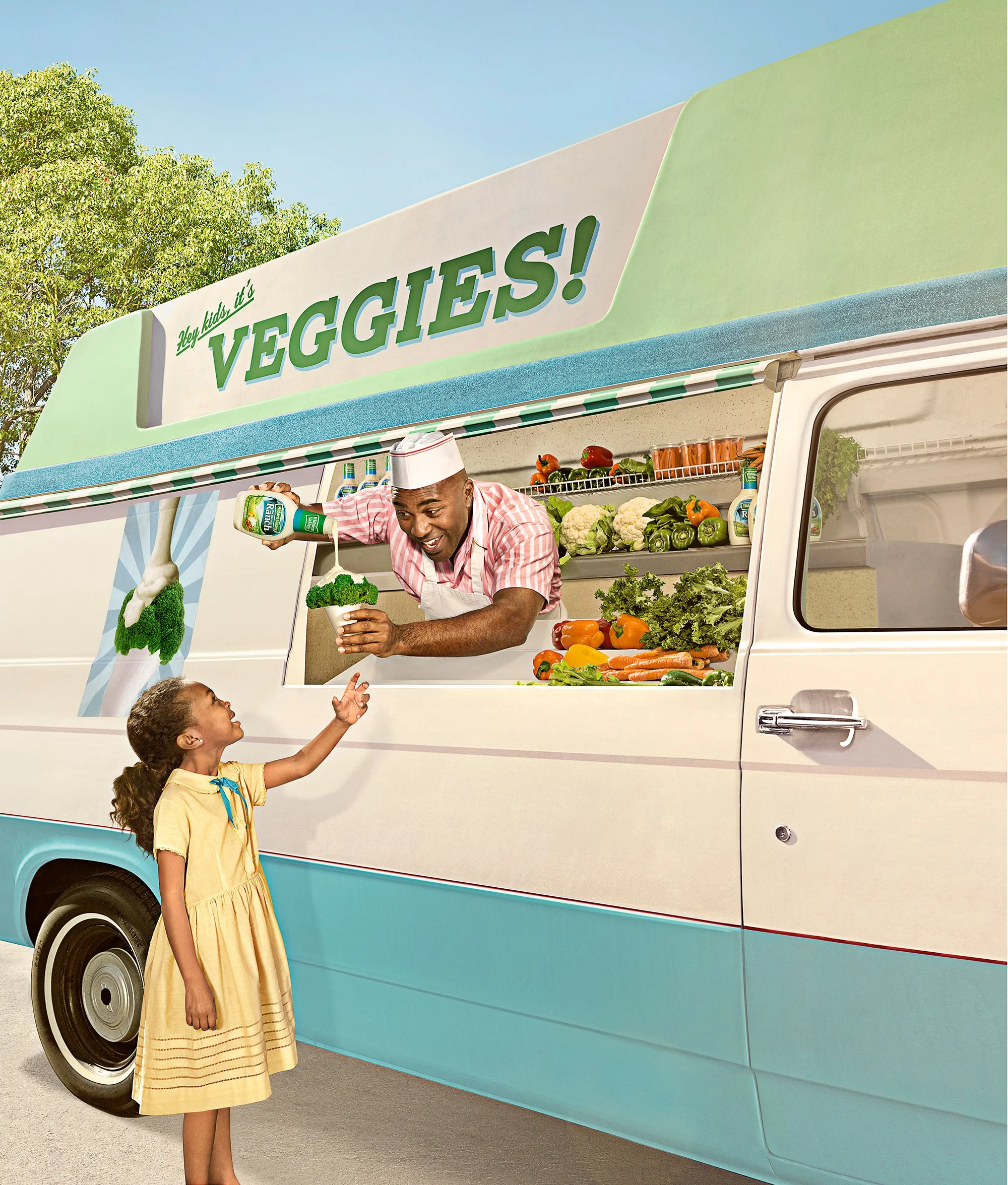 A man working at a veggie food truck handing a bowl of broccoli to a young girl. The truck is decorated with various vegetables and the sign reads, 'Hey kids! it's VEGGIES!'