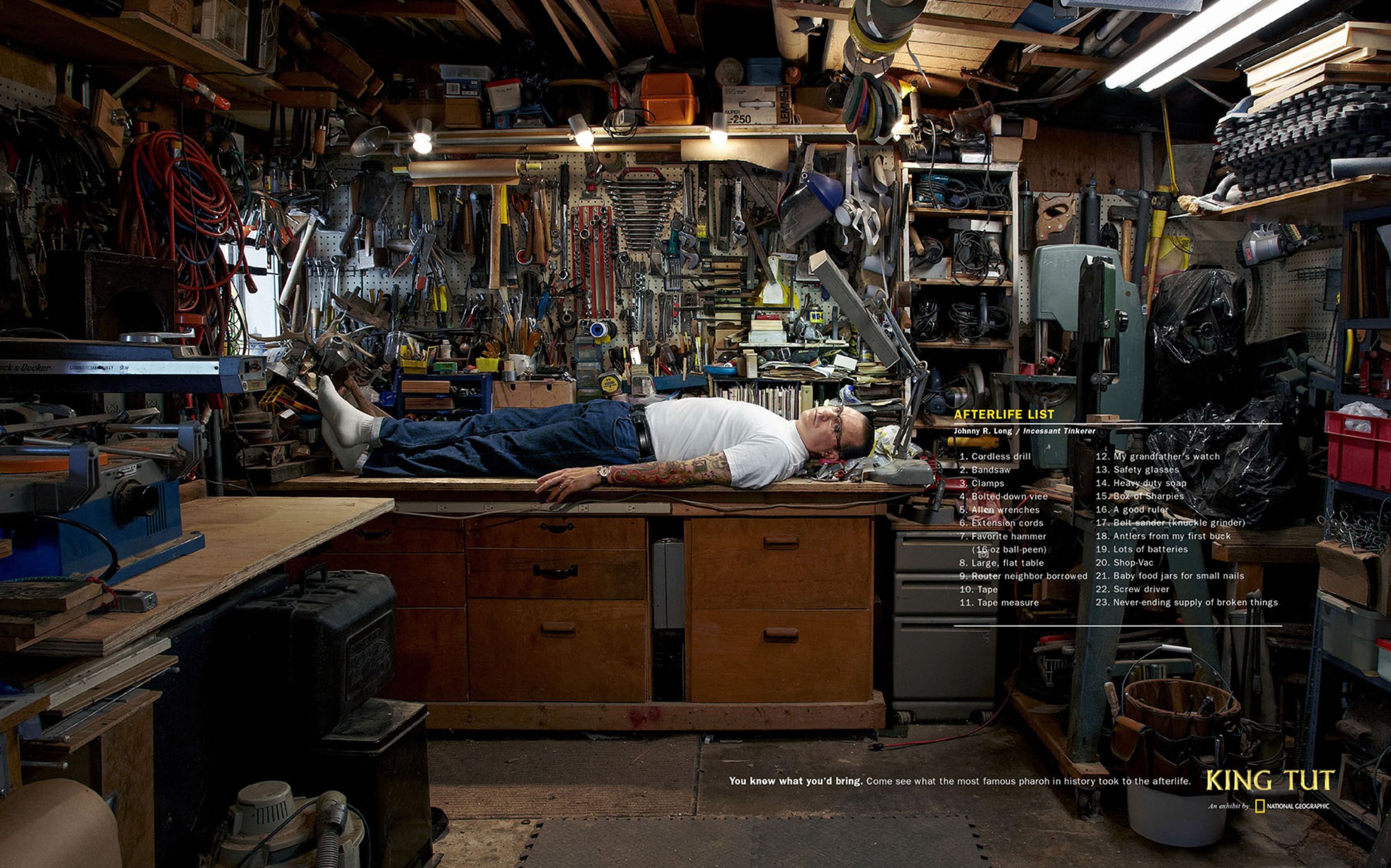 A man lying down on a workbench in a cluttered workshop, surrounded by tools and equipment, with a list titled 'AFTERLIFE LIST' displayed on the right side, and a caption at the bottom mentioning a king named Tut.