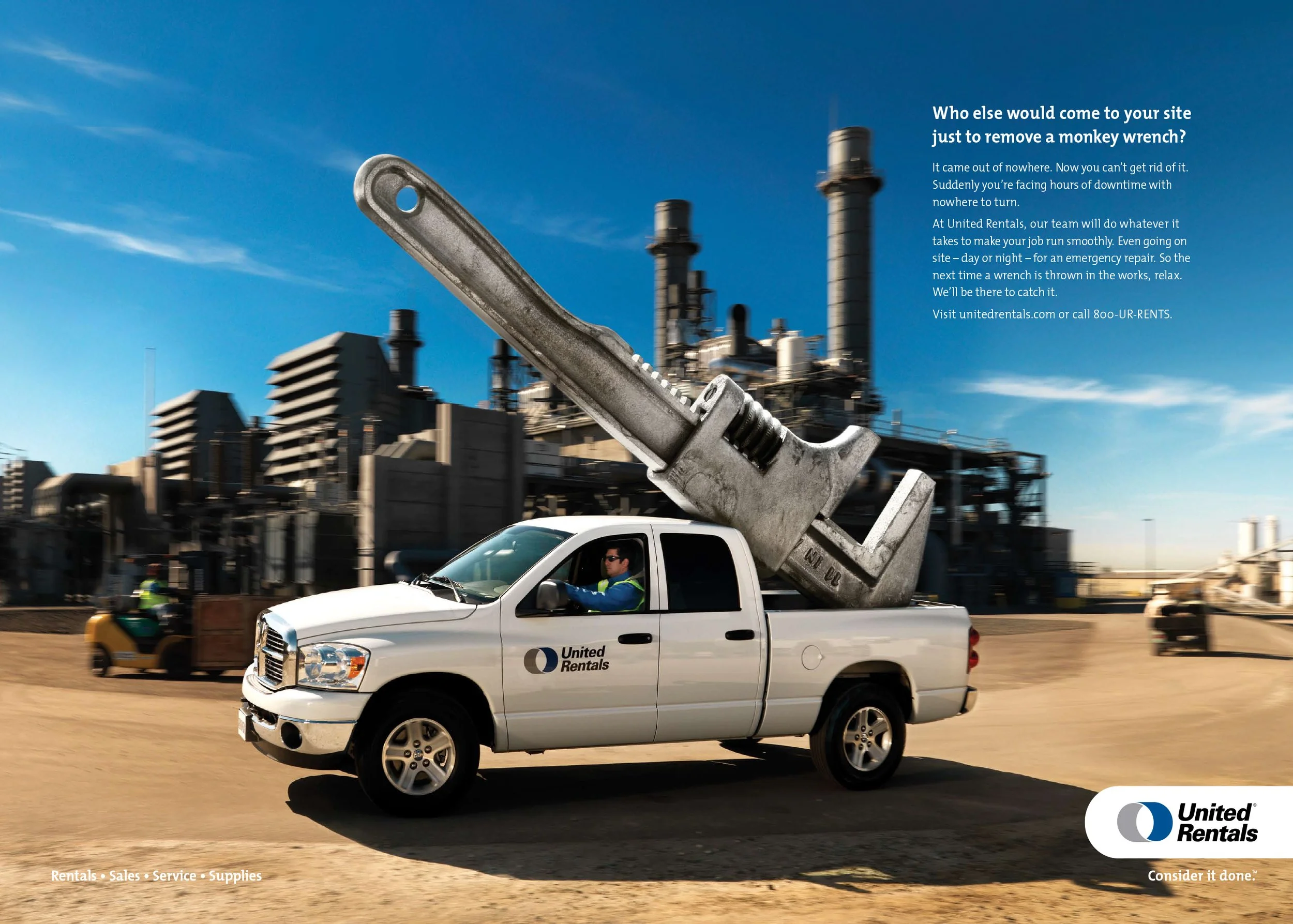 A truck with a large monkey wrench in the back, displaying the United Rentals logo, driving through an industrial area with factories. The ad text questions who would come to a site just to remove a monkey wrench, emphasizing United Rentals' emergenc
