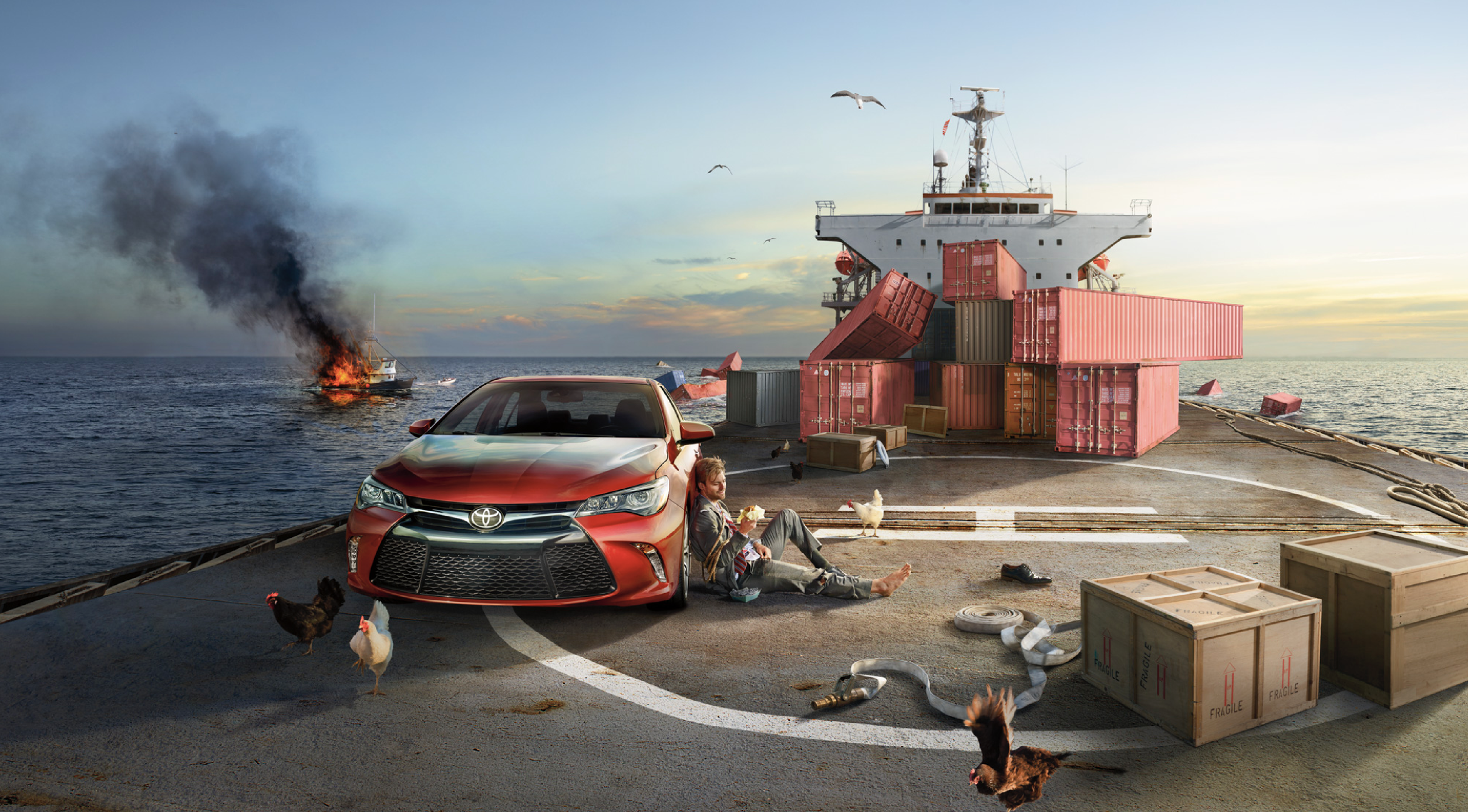 A crashed boat on fire in the sea near a large ship, with a man sitting on the helipad leaning against a red Toyota car, chickens roaming, boxes and debris scattered, and the sunset in the background.