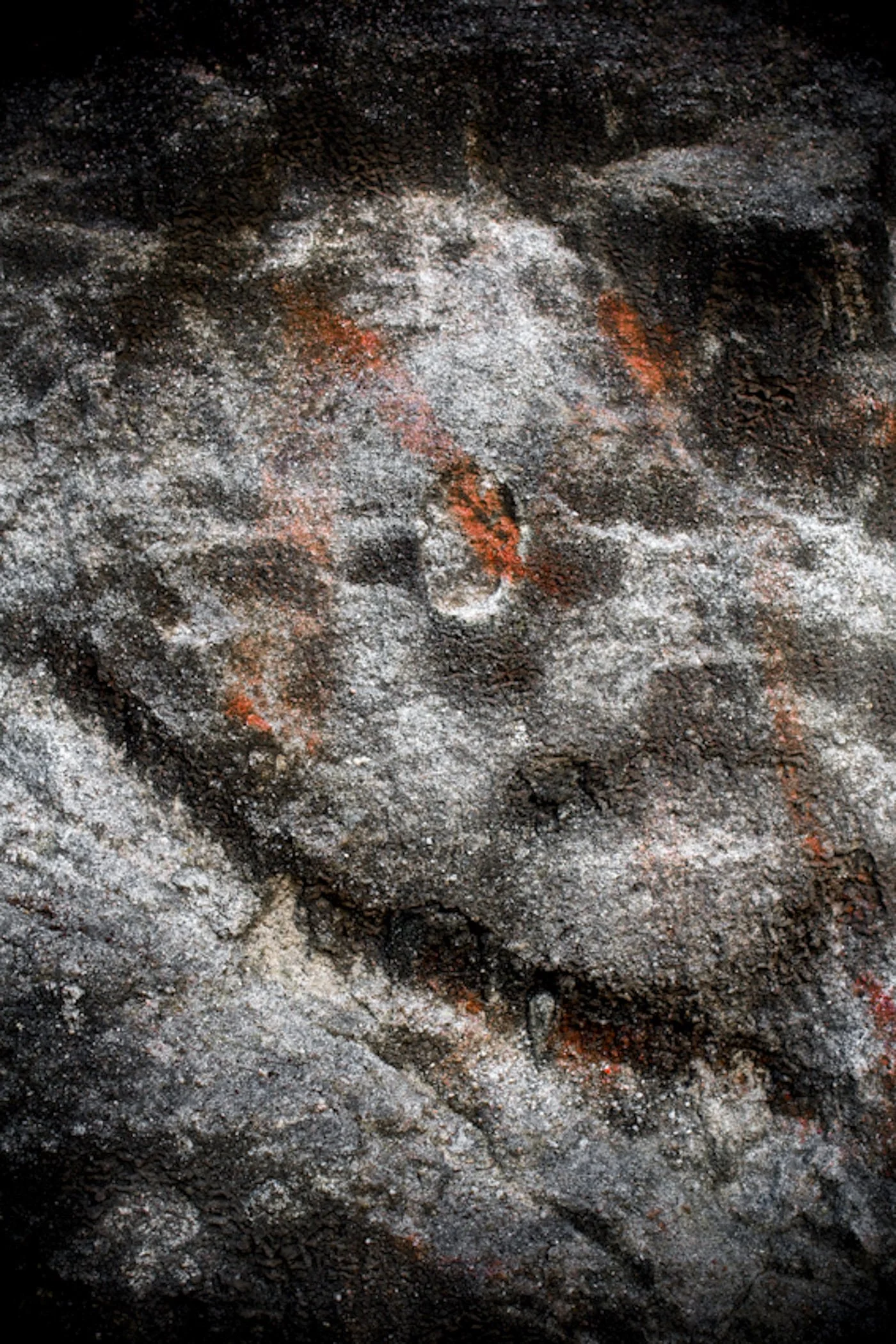 Close-up of dark volcanic rocks with patches of white ash and hints of red-orange glow, volcanic eruption or lava flow.