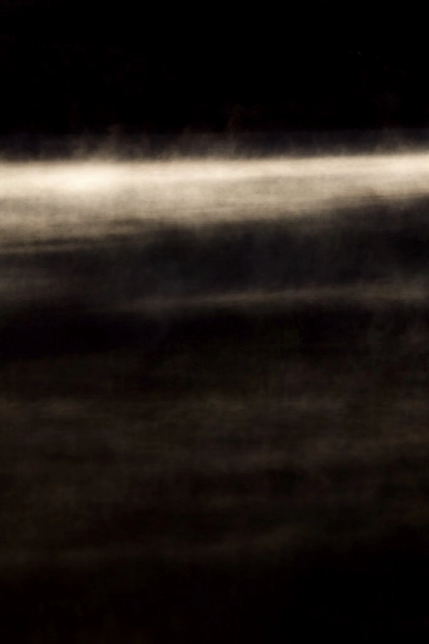 Dark image with faint horizontal light streaks across the middle, unclear details.