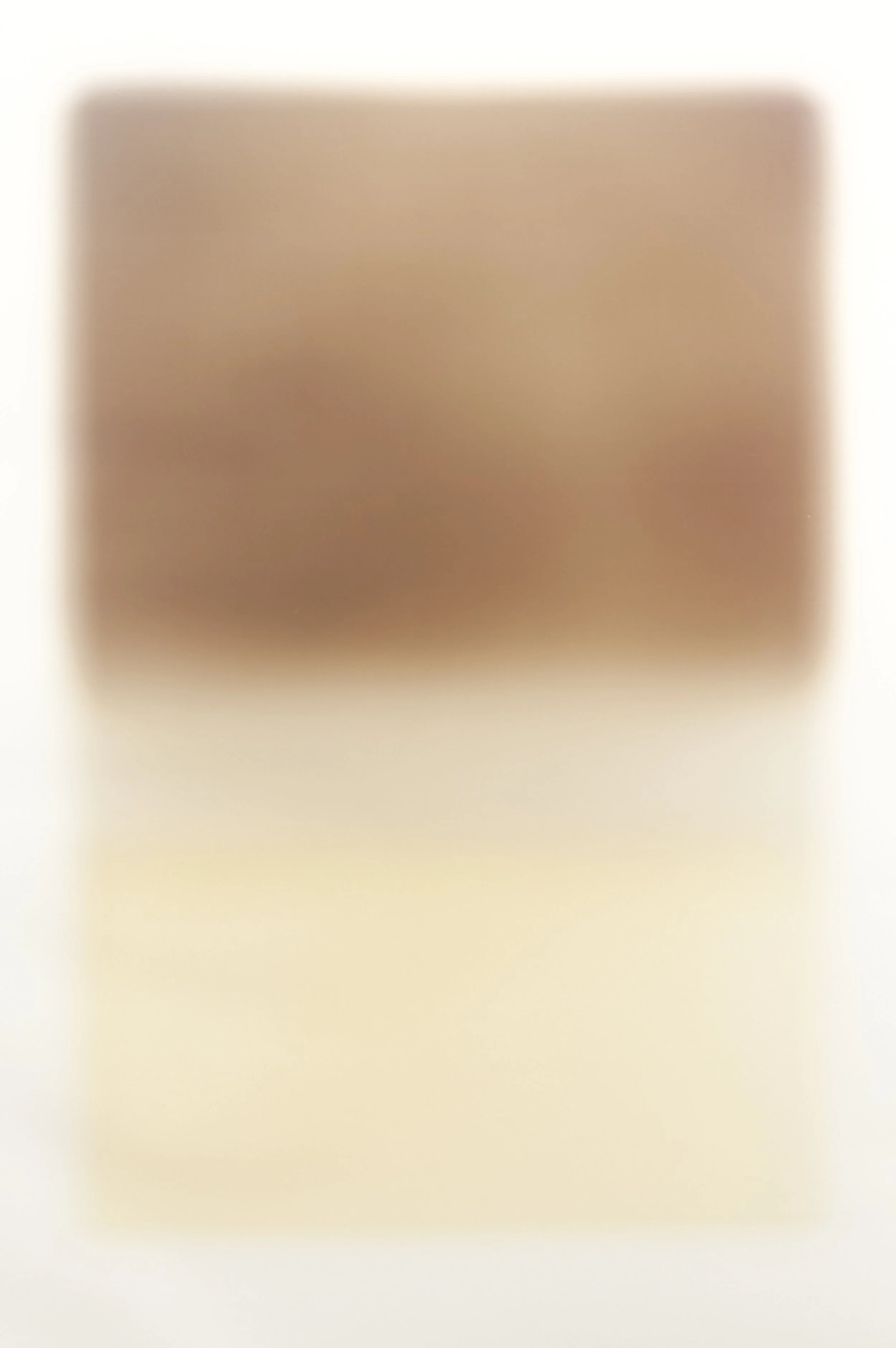 Blurred close-up of a person's hand with light skin tone, resting on a surface.