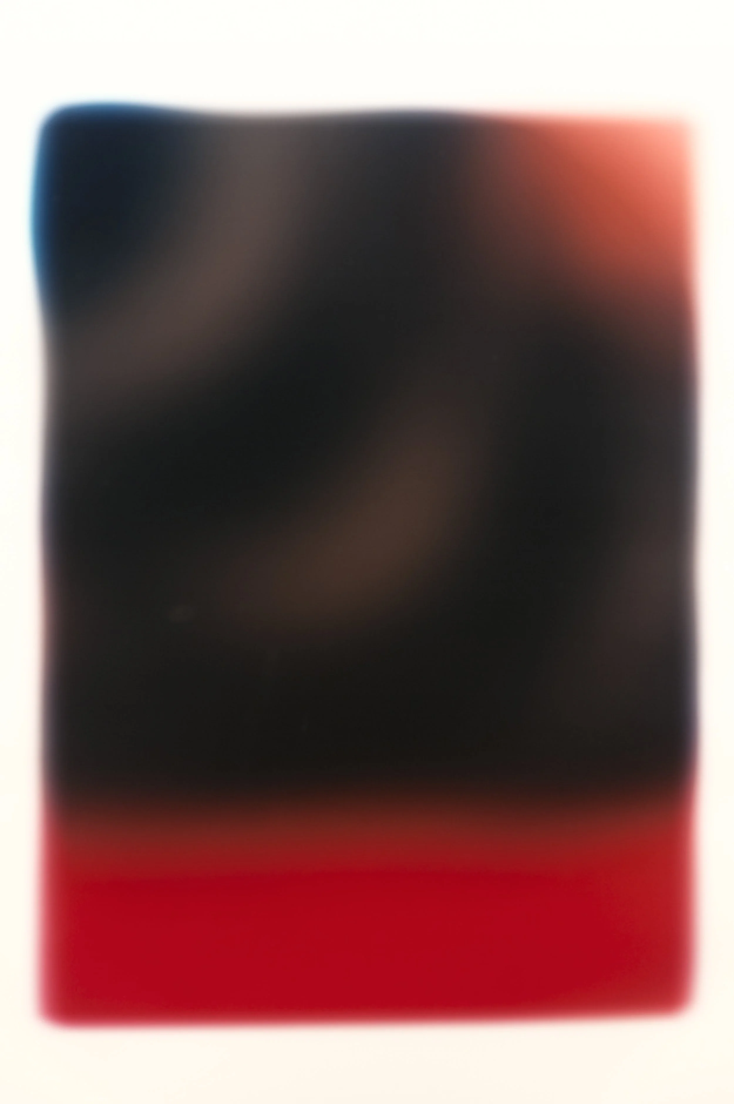 A smartphone capturing a photo of a blurry image with a black, red, and white background.