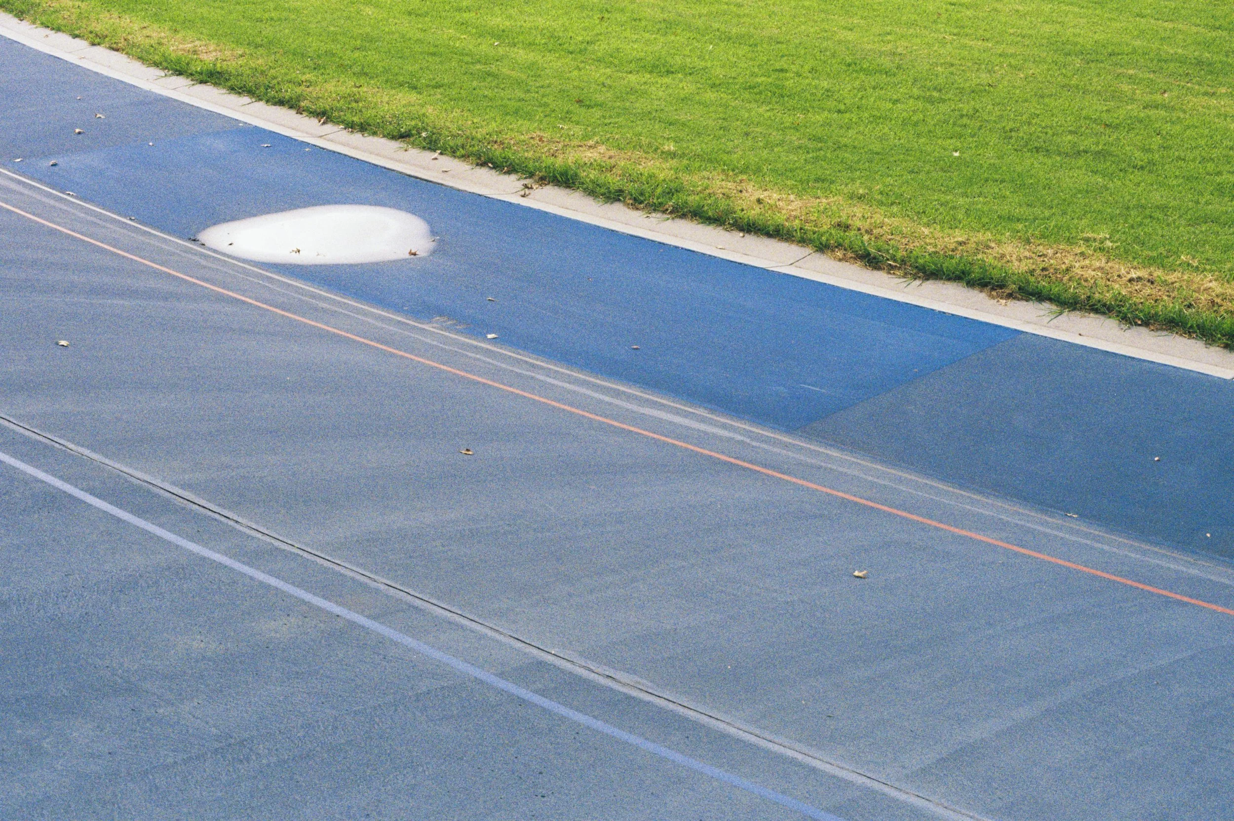 A street with a manhole cover and a grassy area next to the sidewalk.