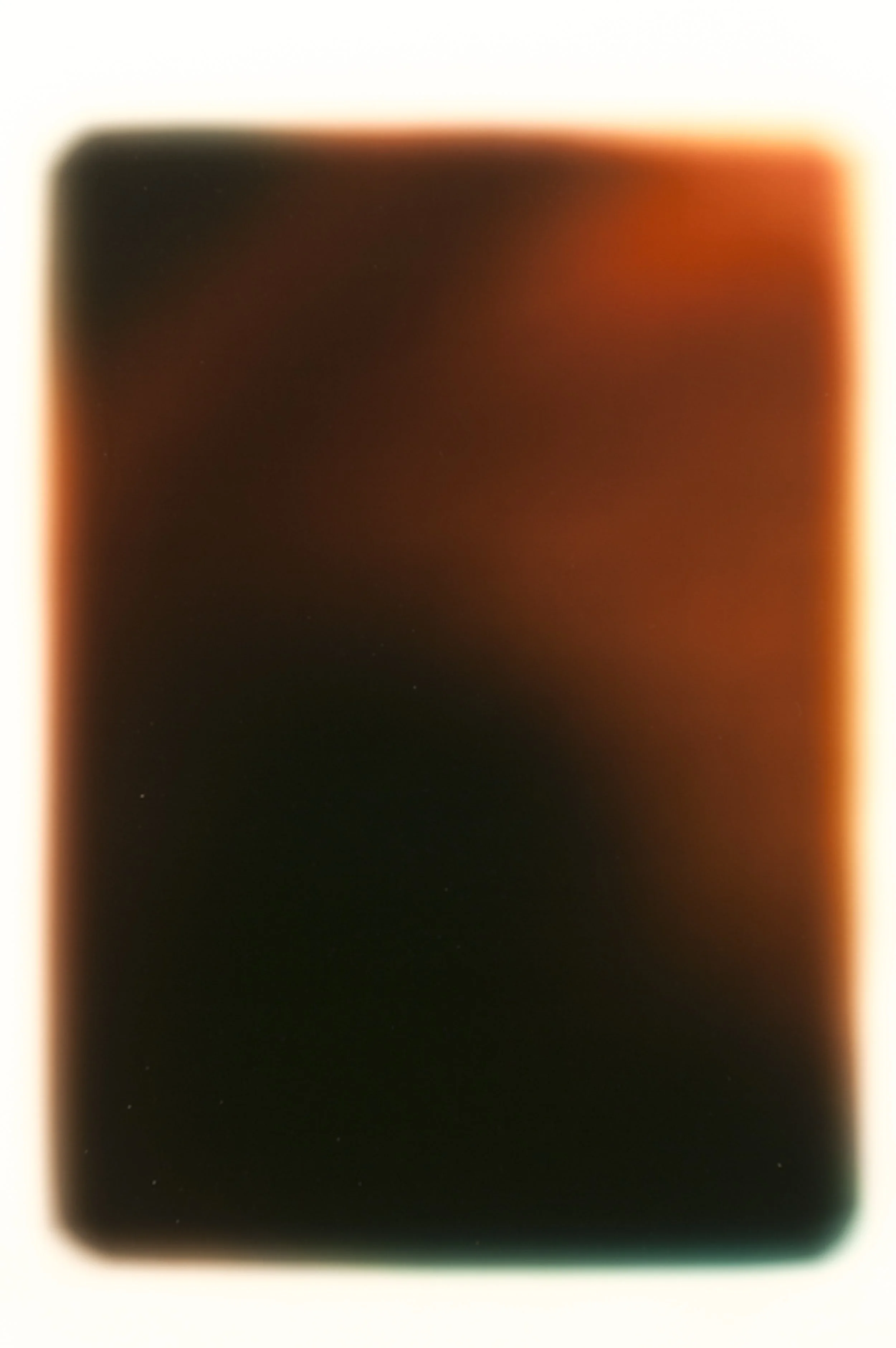 Blurred close-up of a screen or surface with a mix of dark and warm colors, including black, red, and orange, with no distinguishable objects or details.