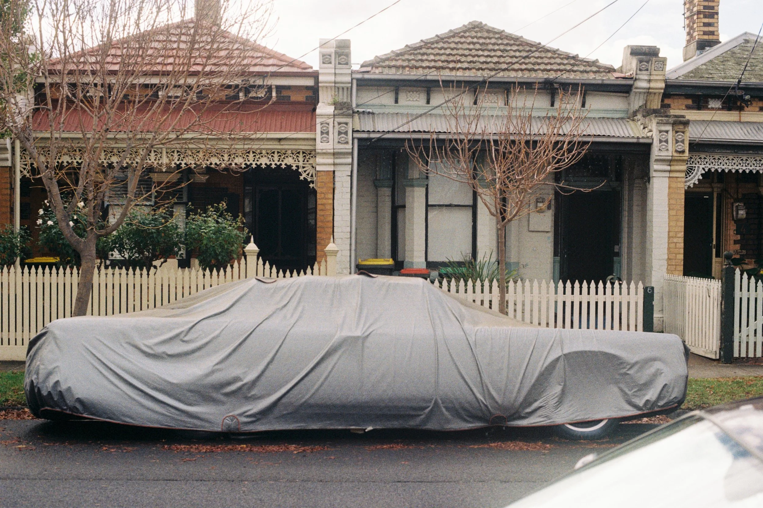 A film photograph of a car that has a cover over it by Christian Pearson