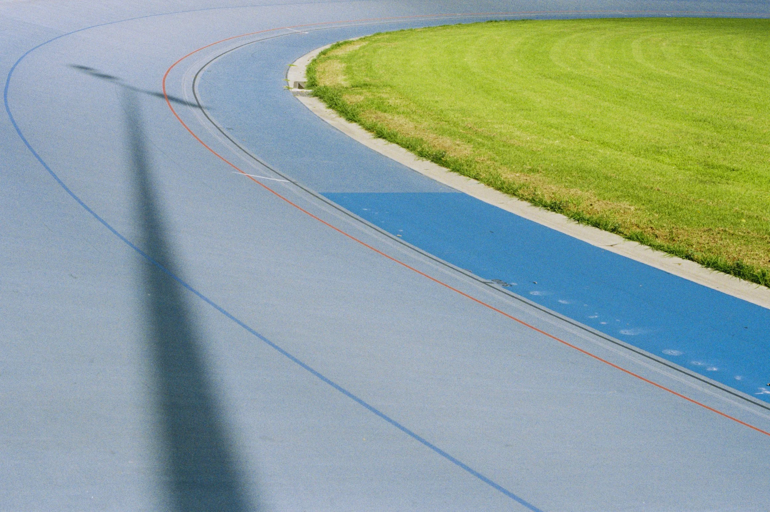 Close-up view of a running track with curved lanes, surrounding a grassy field at an athletic stadium during daytime.