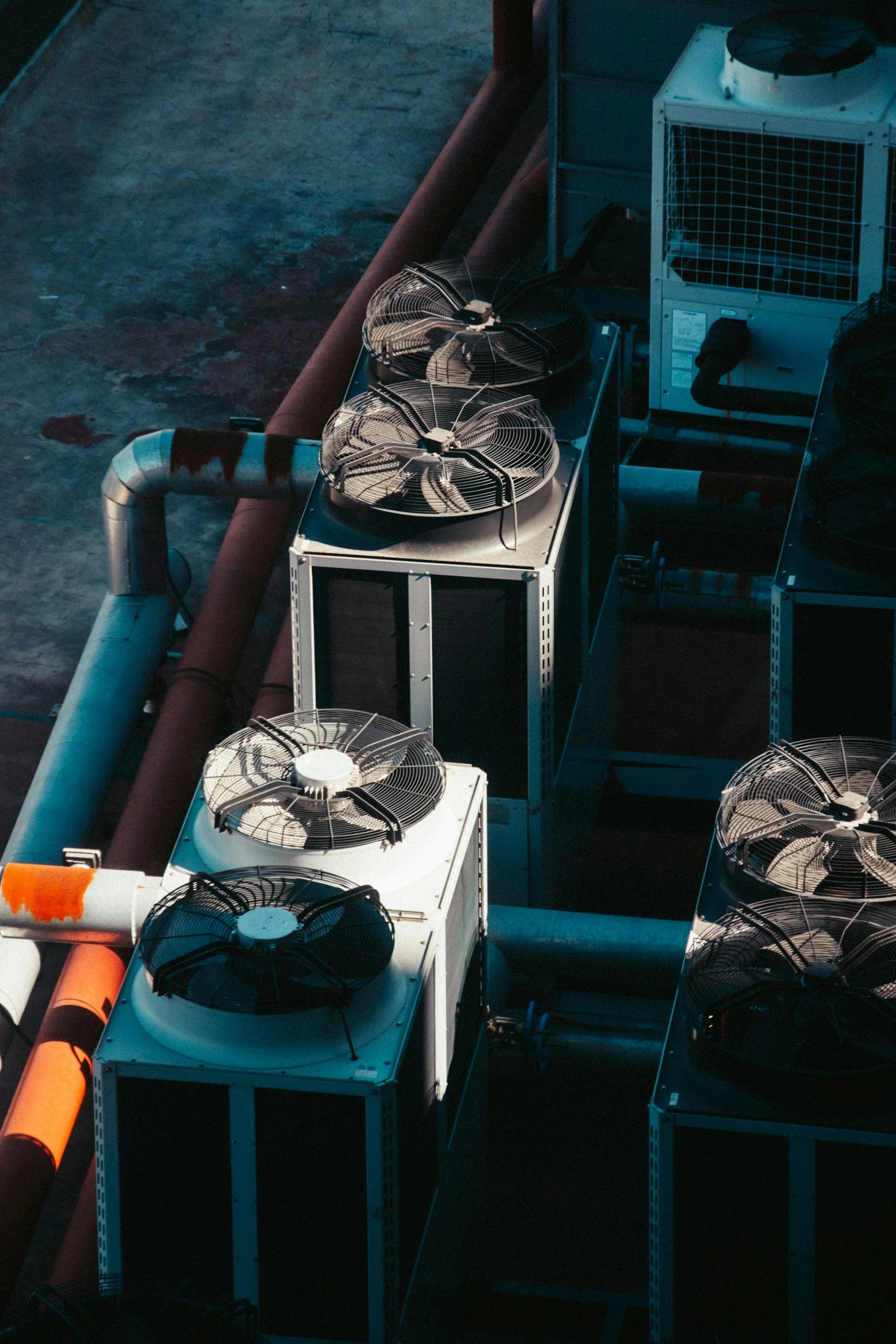 Aerial view of industrial air conditioning units with large fans on rooftops