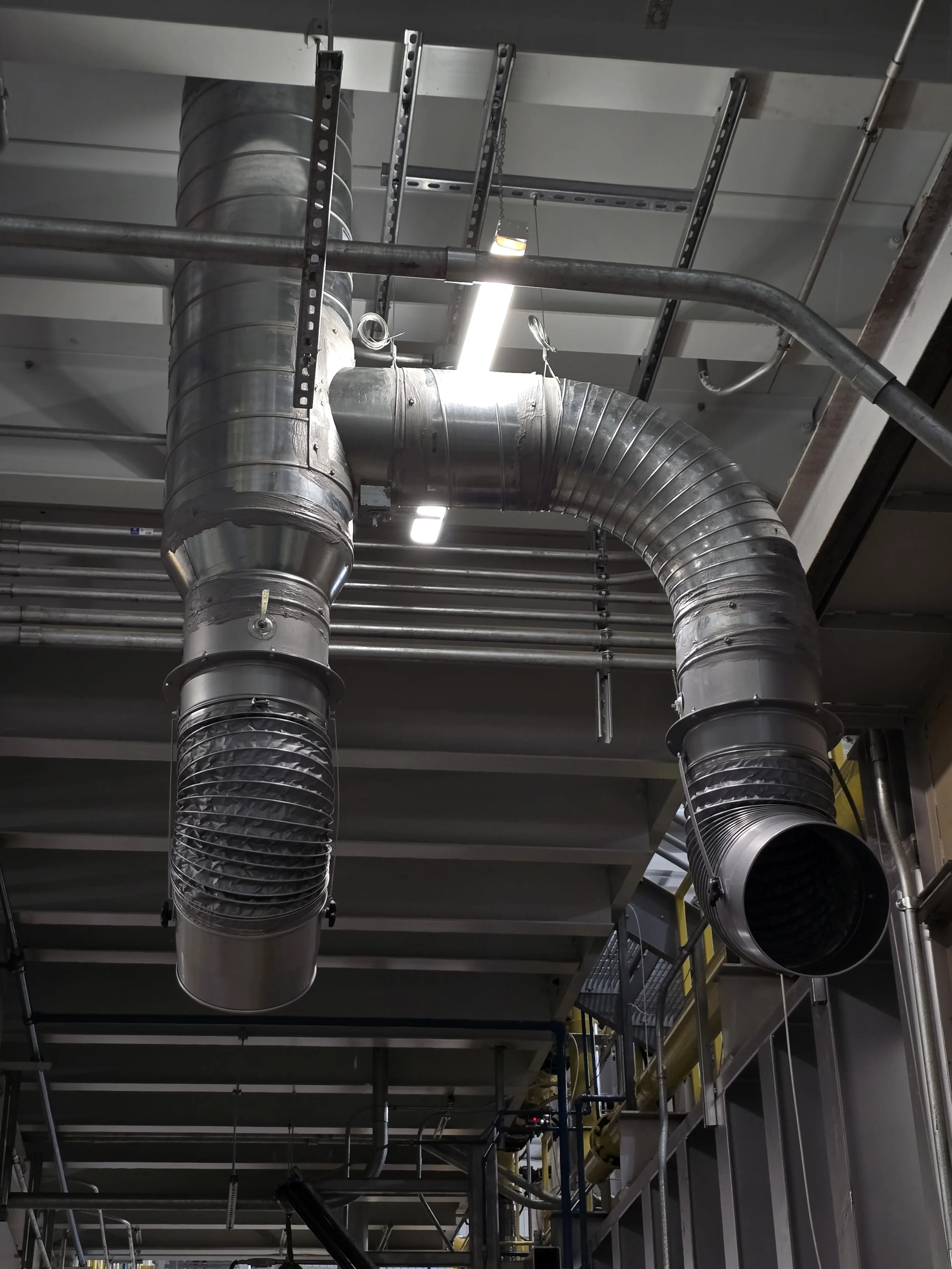 Industrial ventilation system with large metal ducts suspended from a ceiling.
