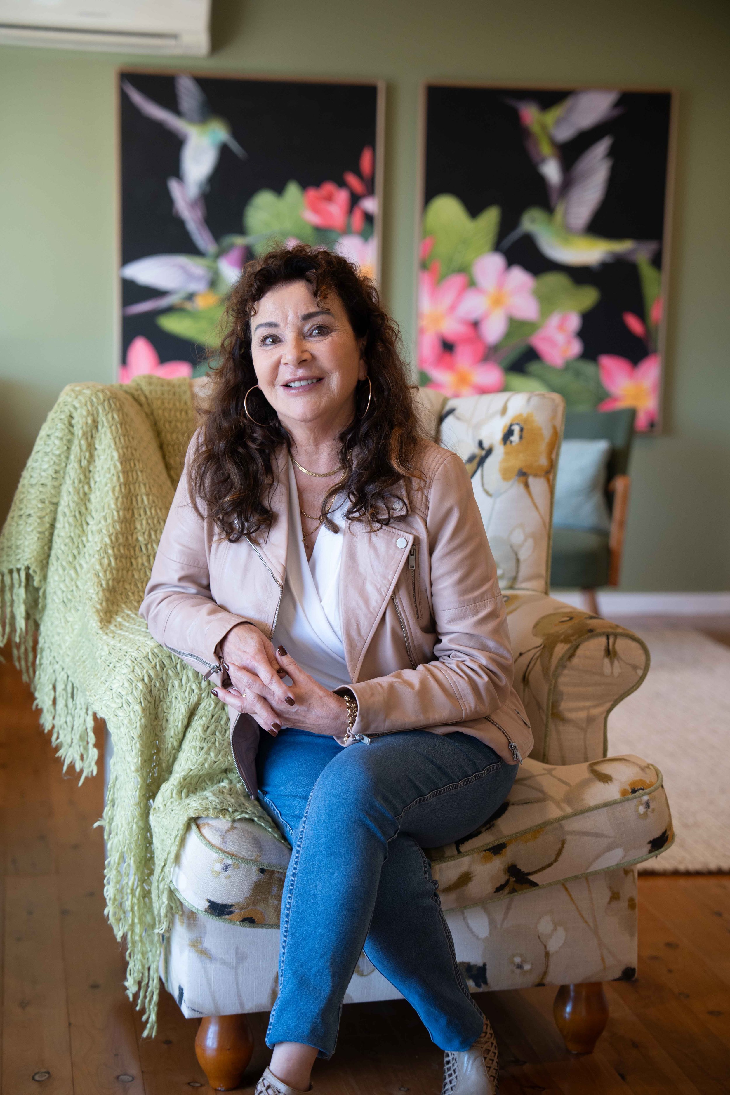 Sue Dalby, Senior Counselling Psychologist, wearing a beige jacket, and blue jeans, sitting in her home office in Toronto, NSW.