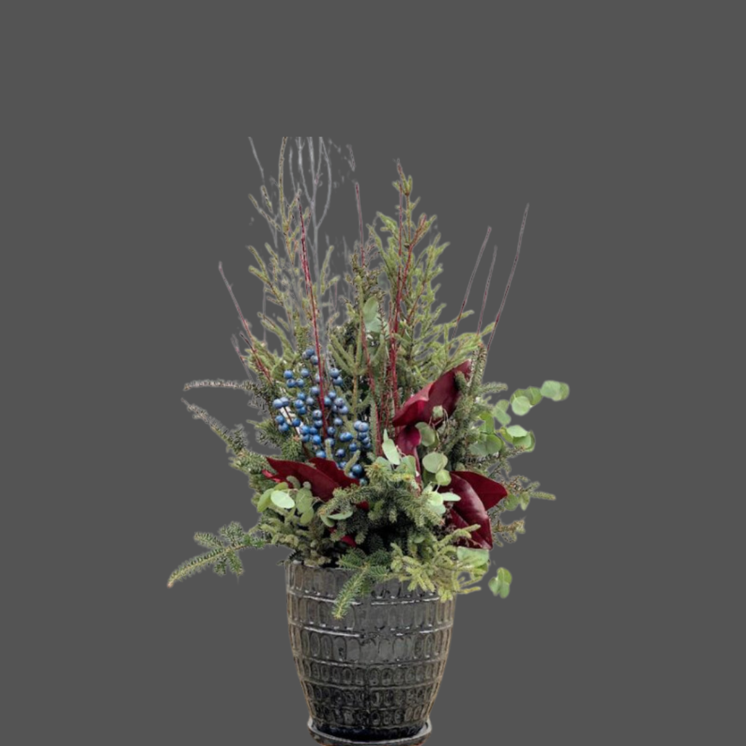 A floral arrangement in a black vase with red, green, and blue elements against a gray background.