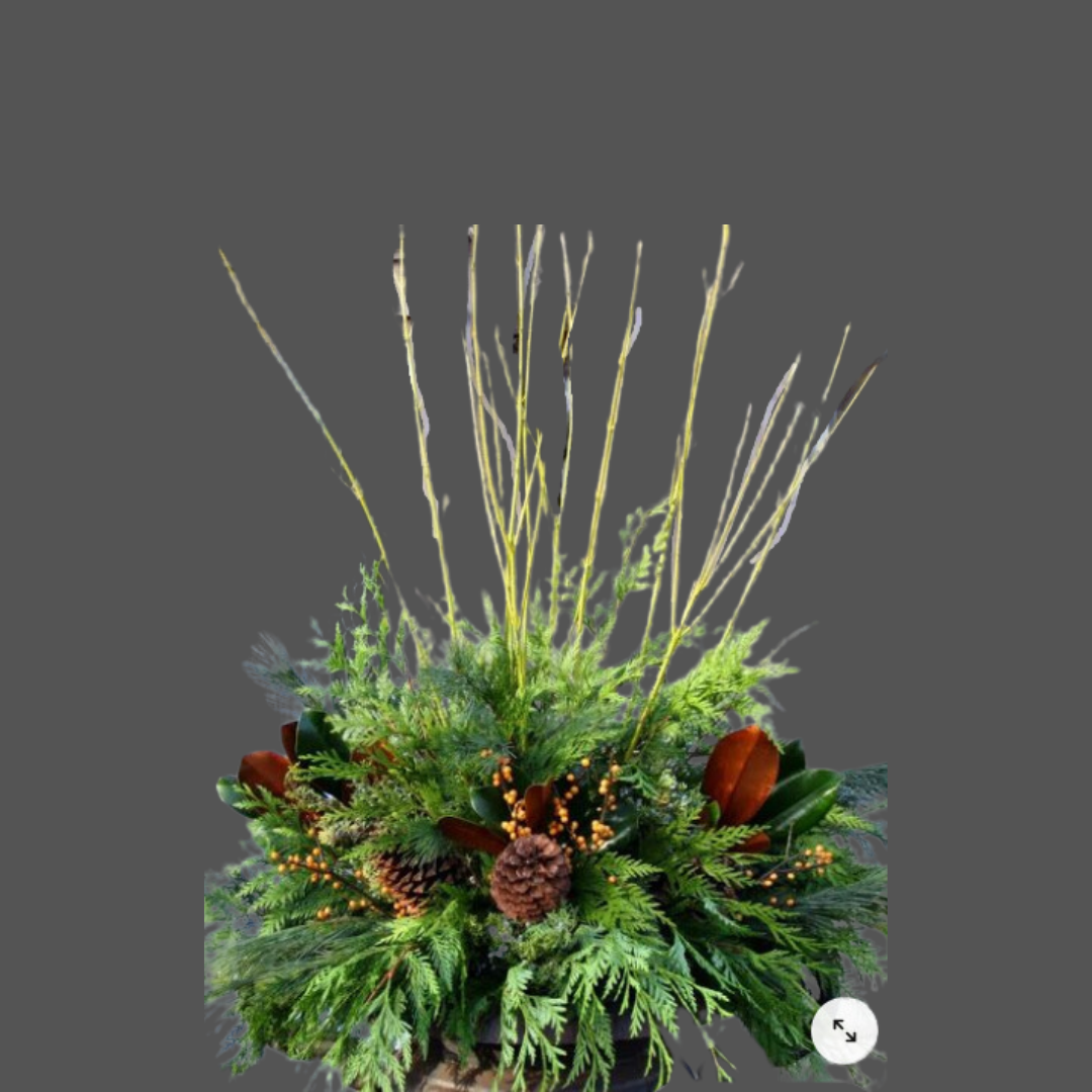 A holiday or winter-themed floral arrangement with pinecones, evergreen branches, and dried grasses or twigs against a gray background.