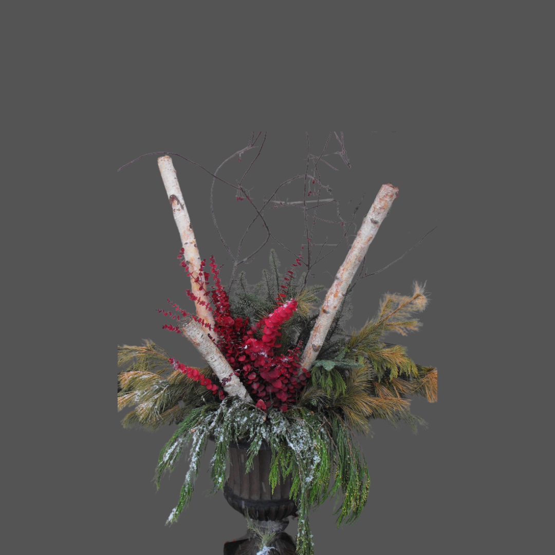 A floral arrangement in a black vase with red, green, and brown foliage, featuring two white birch branches and small red flowers.