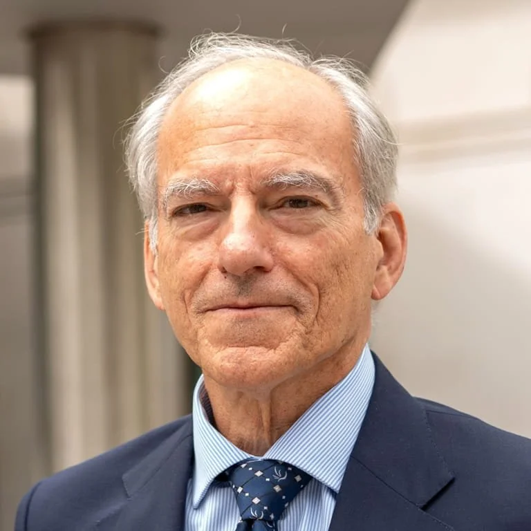 Portrait of an elderly man in a suit and tie, smiling gently.