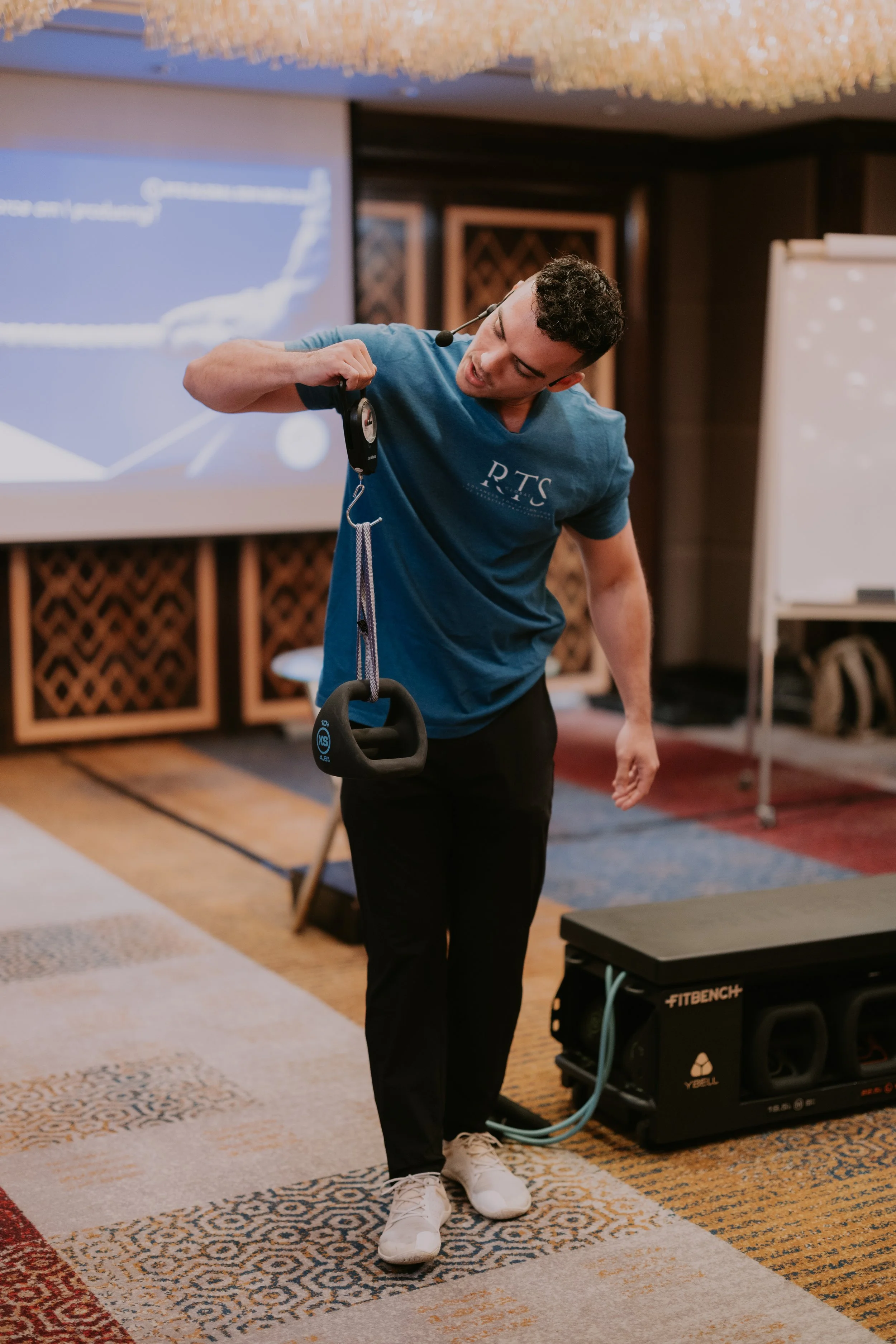 Benny Price demonstrating how tempo and inertial effects impact the forces experienced by lifters at a conference