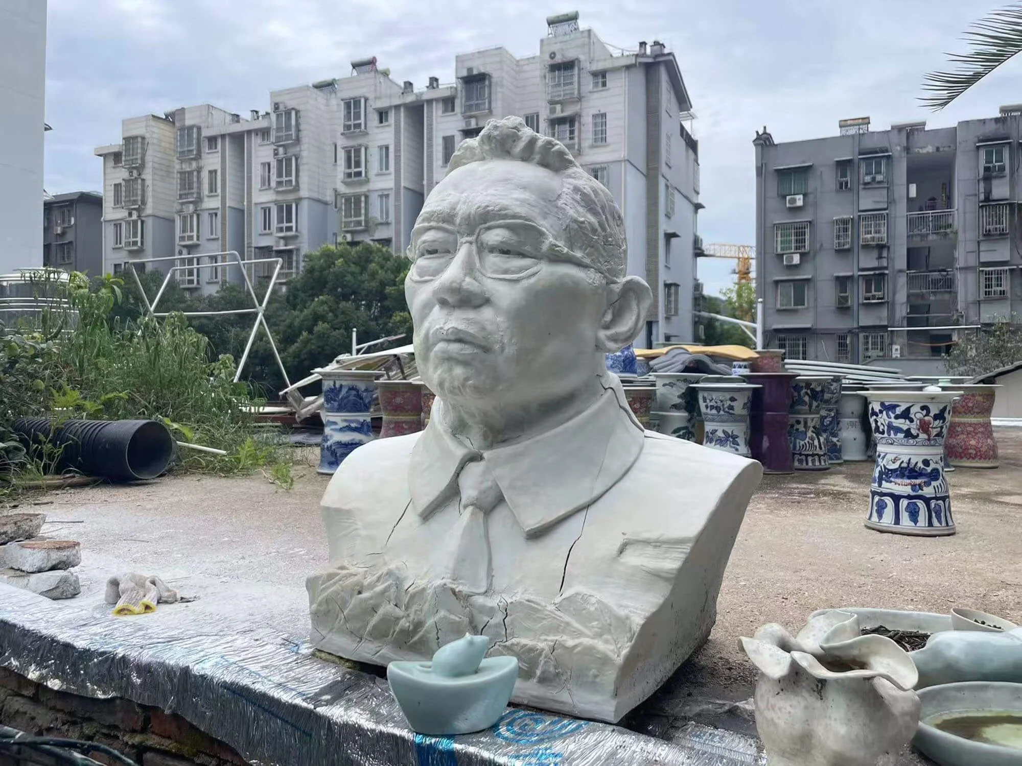 Sculpture of male bust in Jingdezhen, China, surrounded by porcelain works.