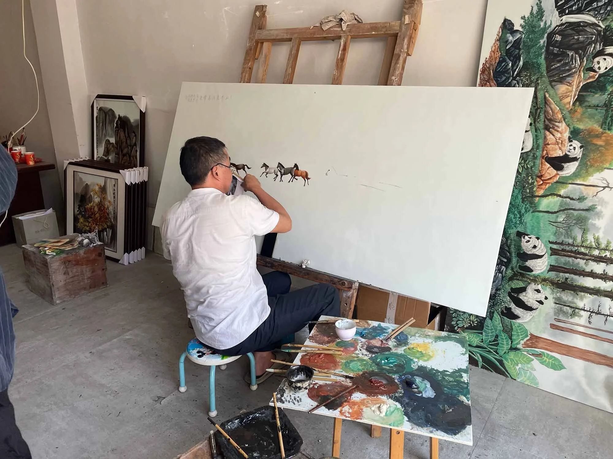 Artist painting canvas panel in workshop in Jingdezhen, China.