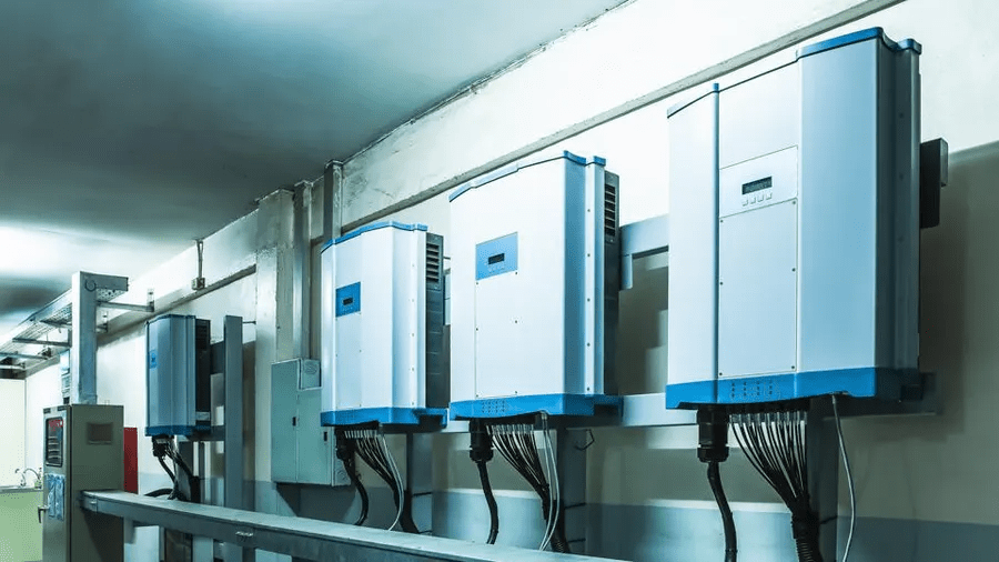 Multiple white and blue industrial inverter or transformer units mounted on a wall in an industrial or server room.