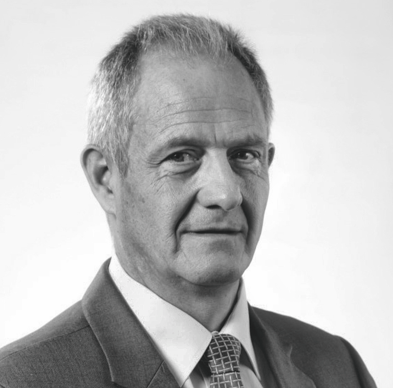 Black and white portrait of a middle-aged man with short, receding hair, wearing a suit, shirt, and patterned tie.