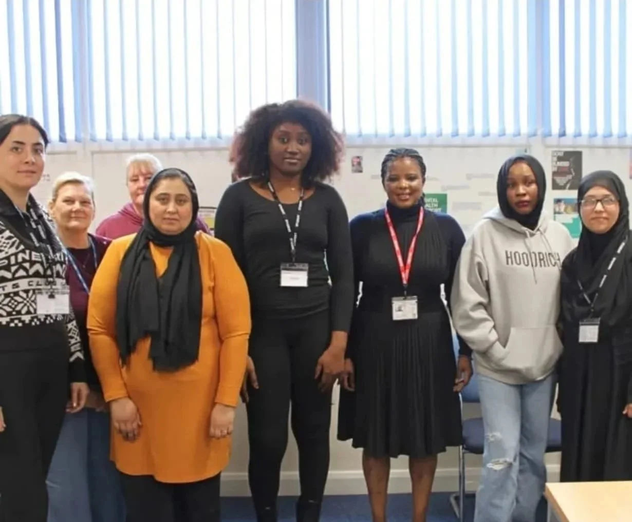 A modern house on a green hillside with snow-capped mountains in the background.