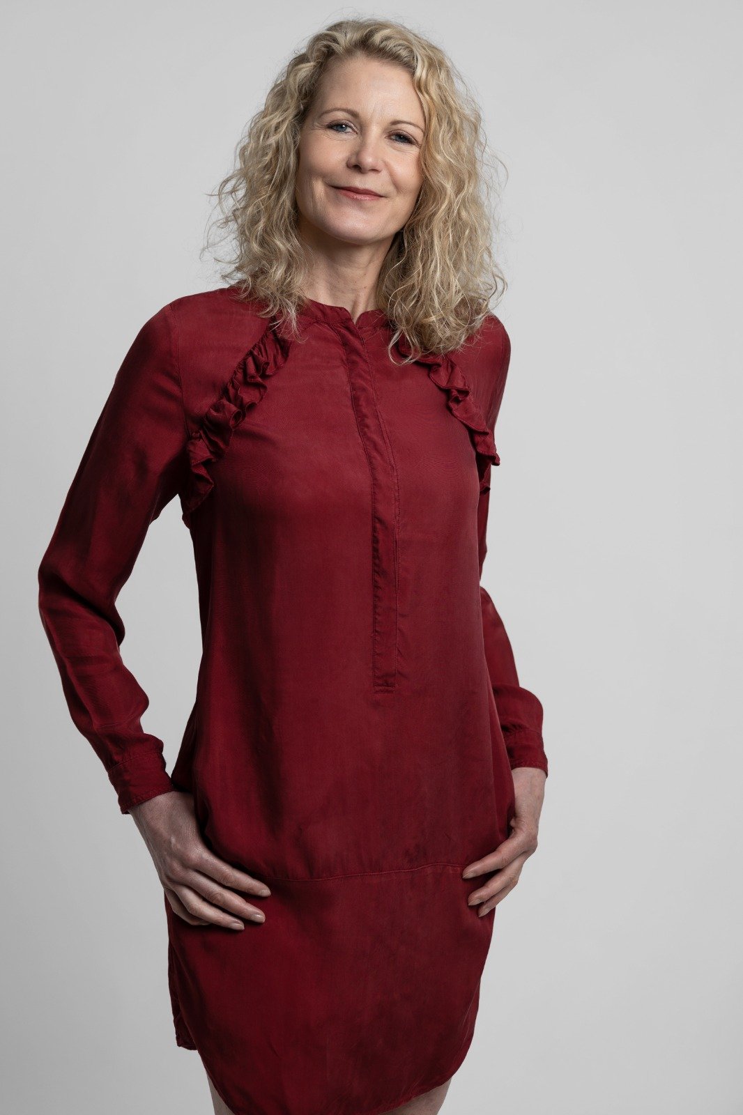 Mirella lapre in een rode jurk in haar praktijk voor nei therapie, retreats en traumaverwerking