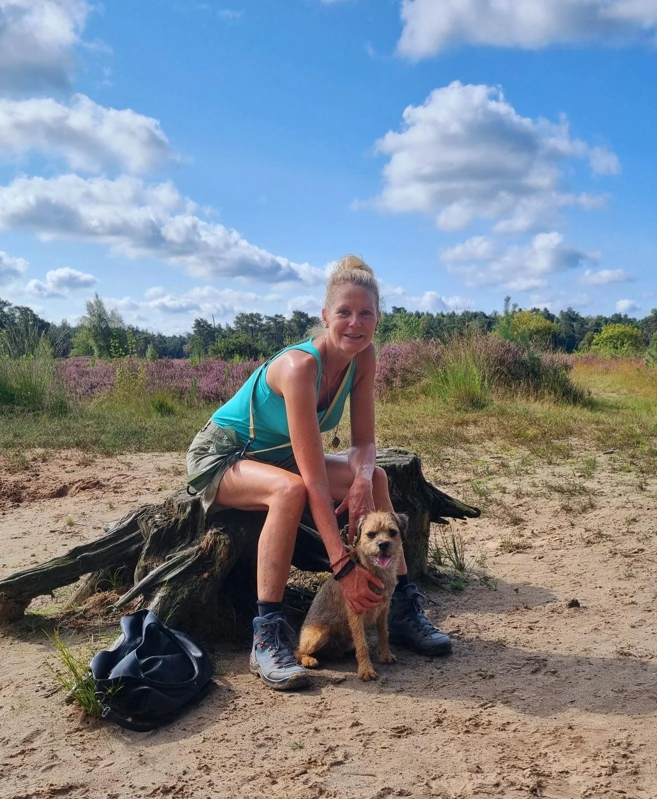 Een nei-therapeut zit op de heide met haar hond tijdens een ontspannen wandeling.