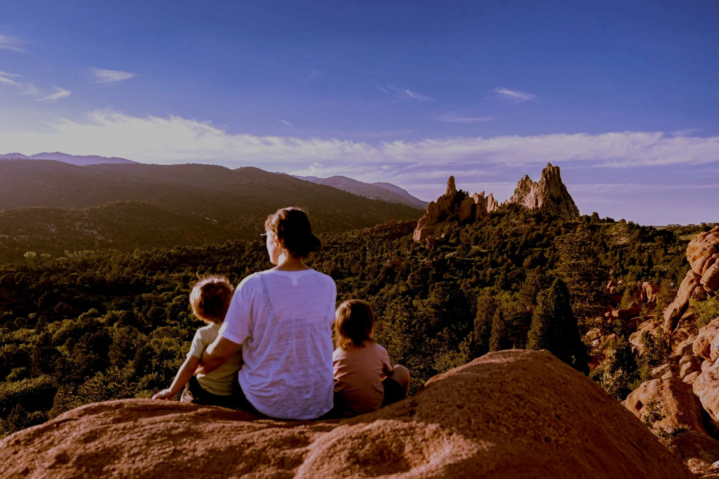 Woman with two children overlooking a mountain scene in Europe