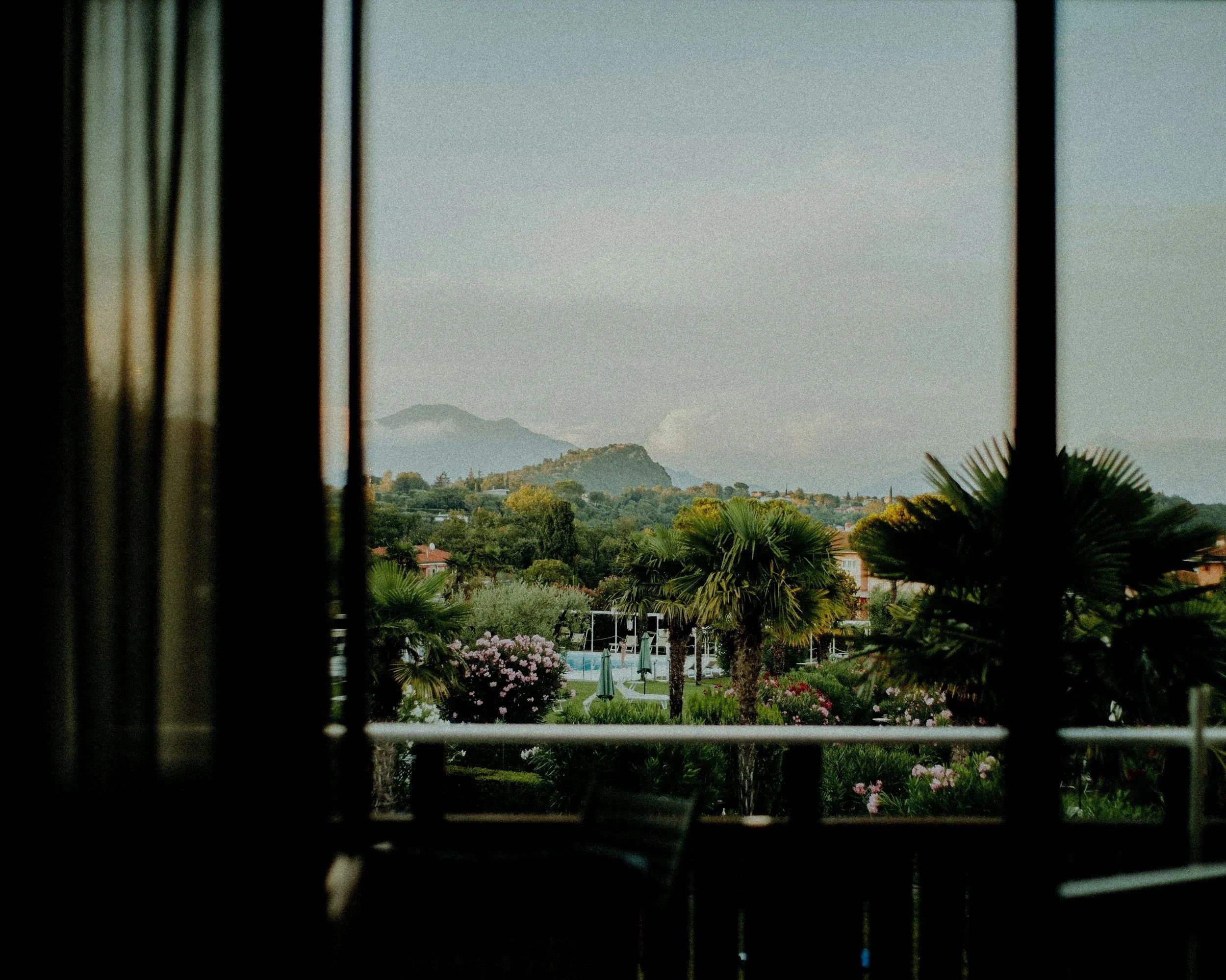 View from a hotel room of a pool with palm trees and flower 