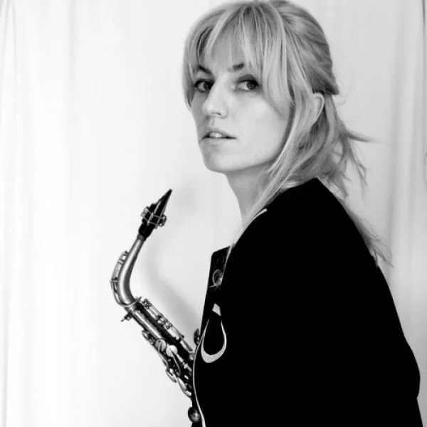 Black-and-white photo of a woman with blonde hair holding a saxophone.