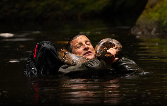 Mann im Wasser hält eine Schlange um den Hals.