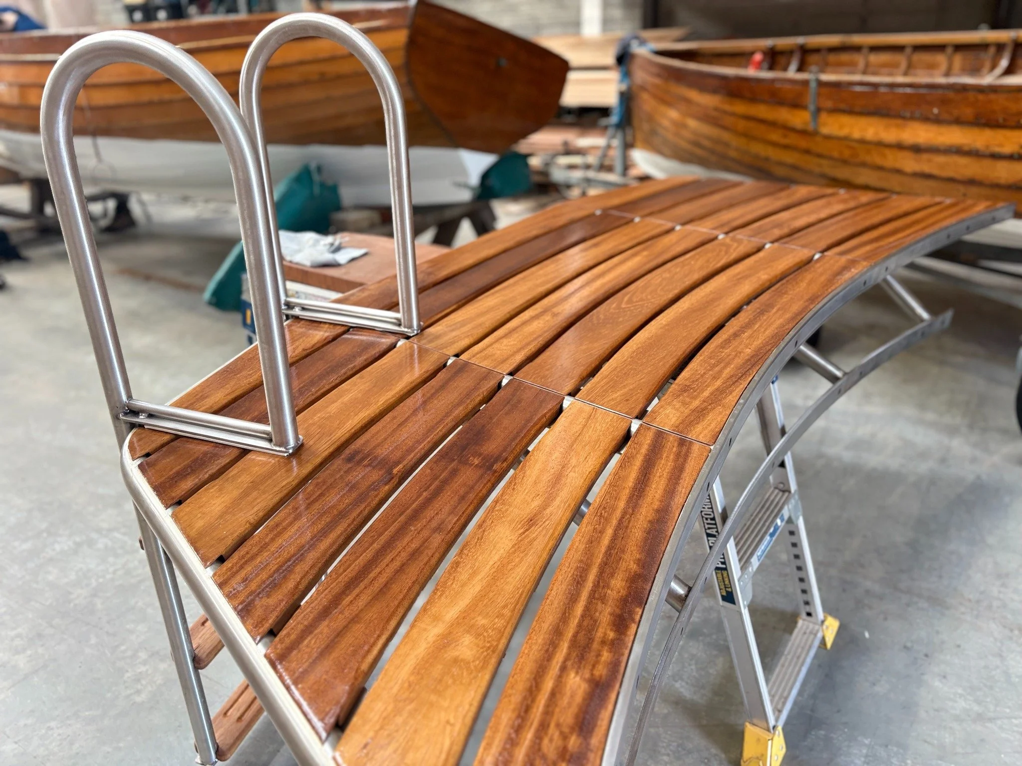 Custom timber swim platform with curved decking, metal frame and ladder built by McLoughlin Boat Company