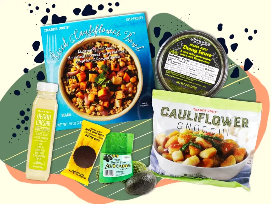 Assorted vegan food products including a Trader Joe's cauliflower bowl, cauliflower gnocchi, vegan Caesar dressing, chocolate cupcake liners, an avocado, and a container of tzatziki sauce, arranged on decorative background.